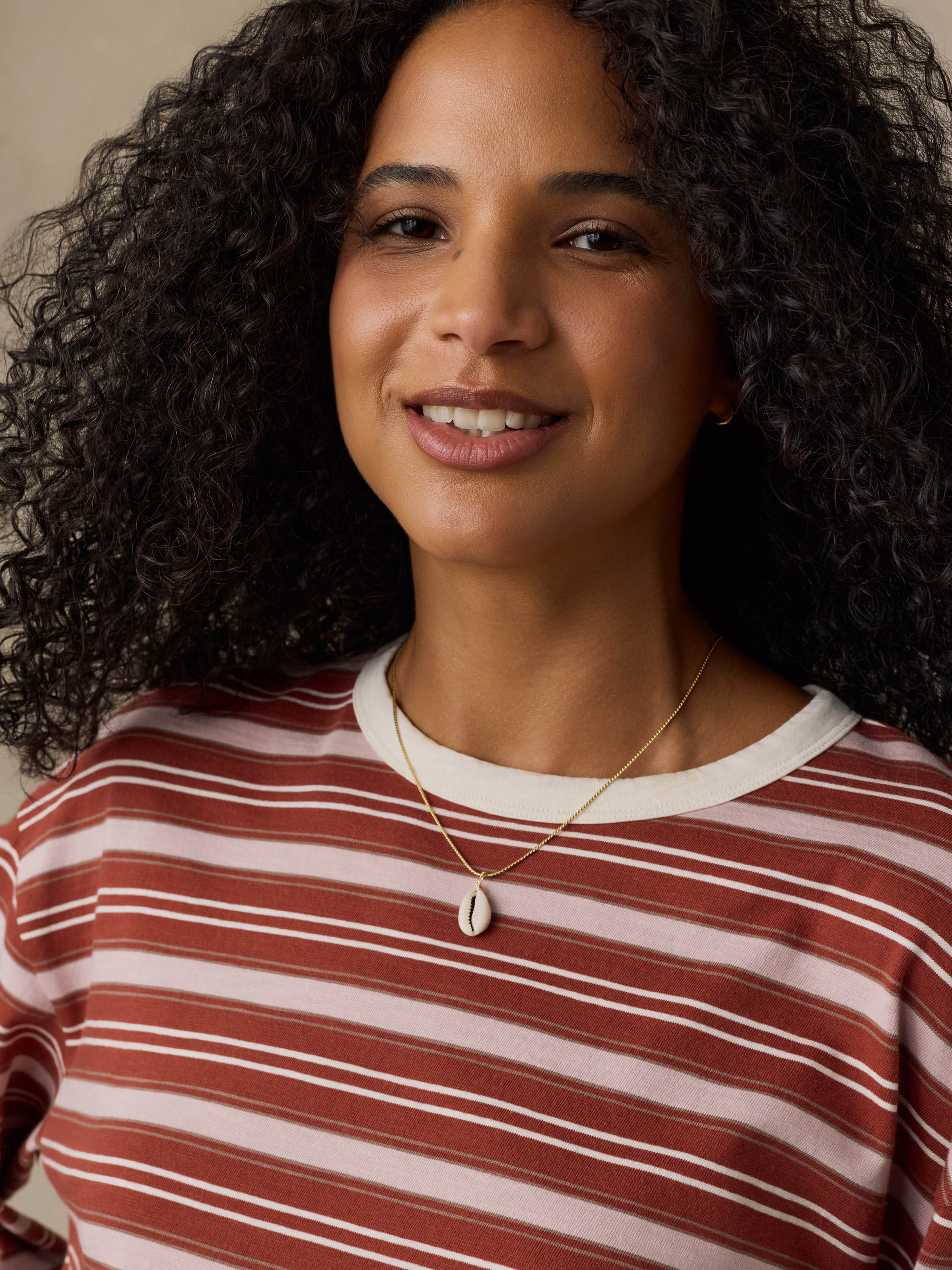 Woman wearing a red and pink striped long-sleeve shirt against a beige background