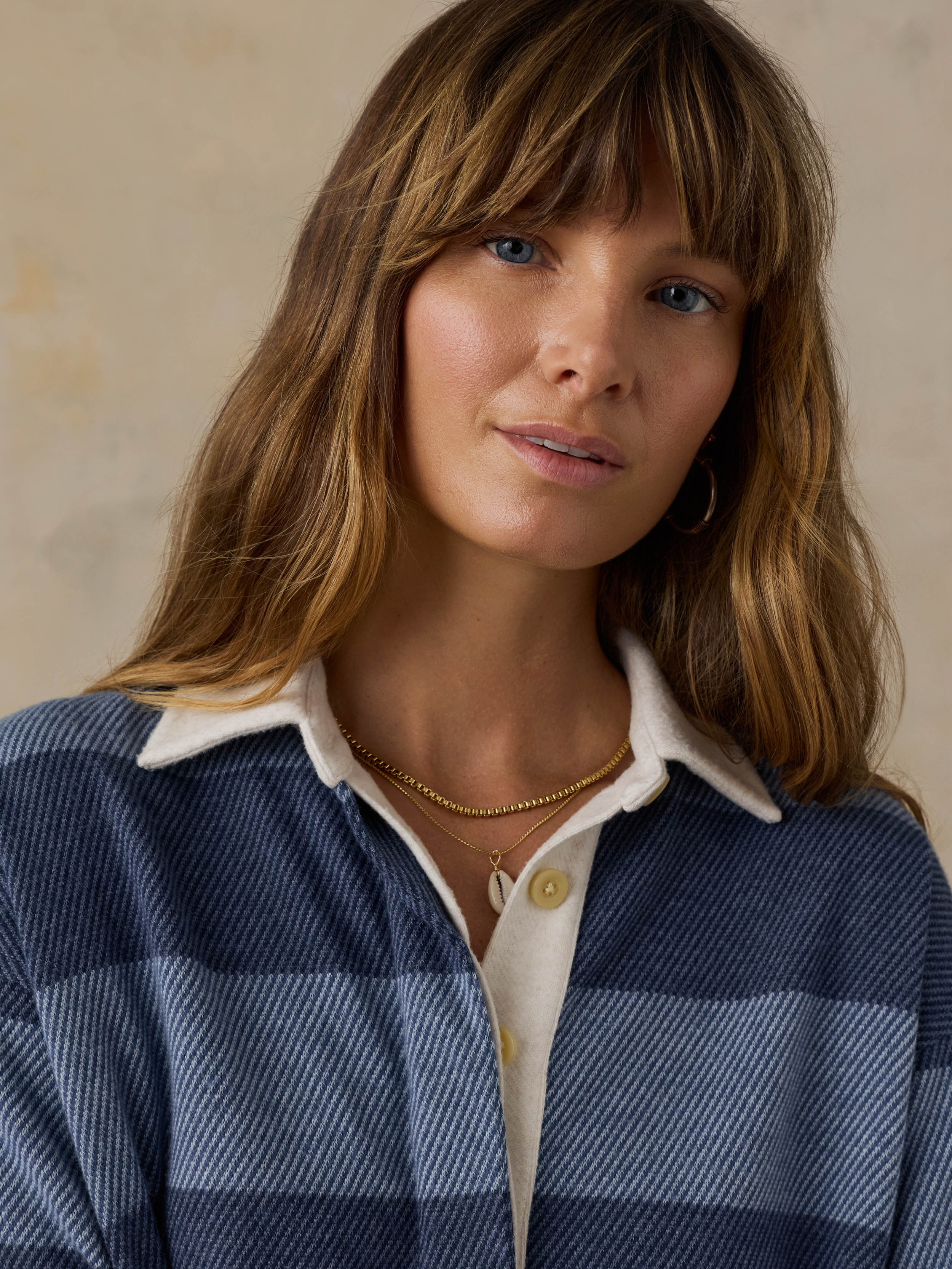 Woman wearing a blue striped rugby shirt against a beige background