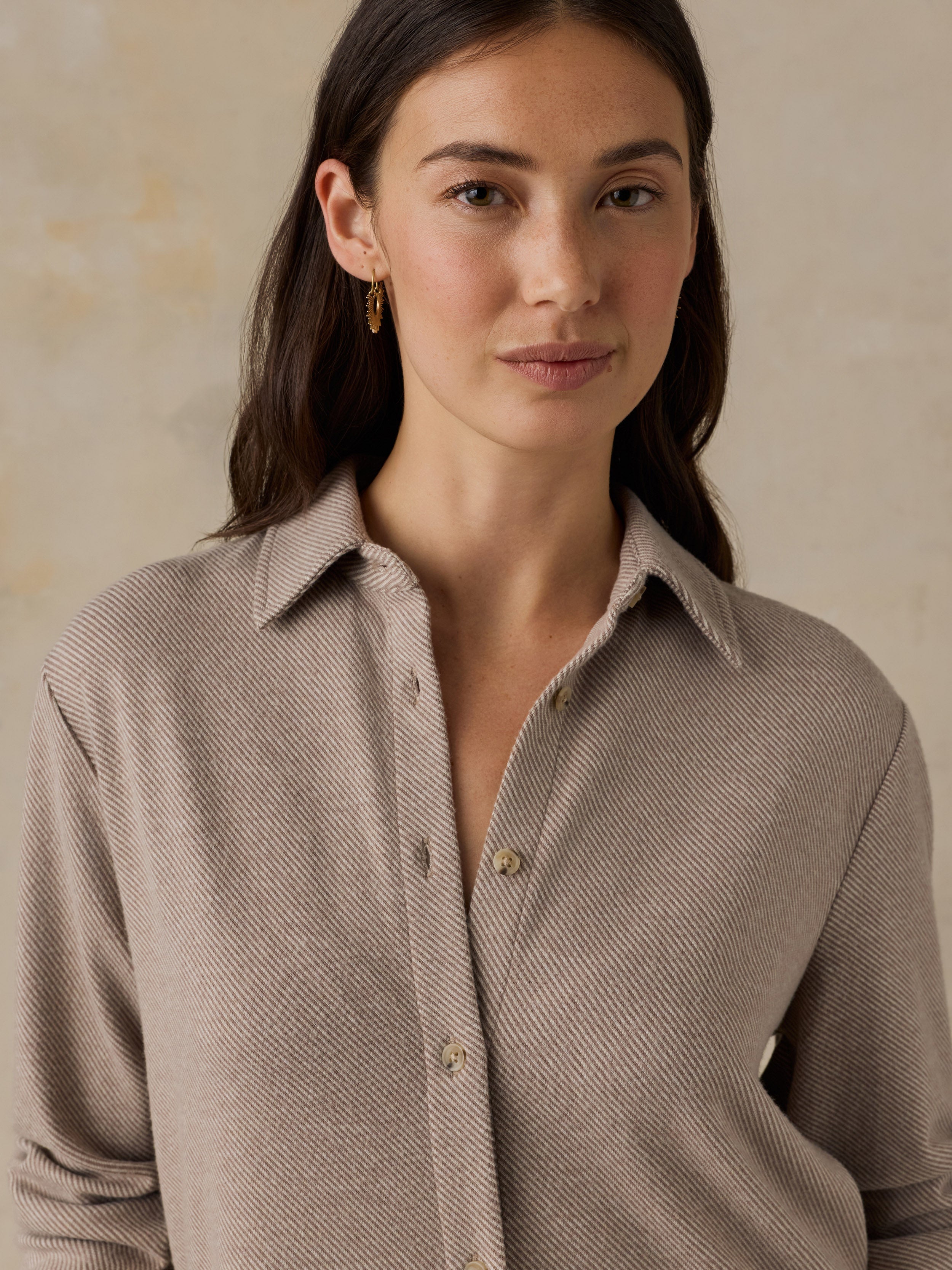 Woman wearing a beige button down shirt against a beige background