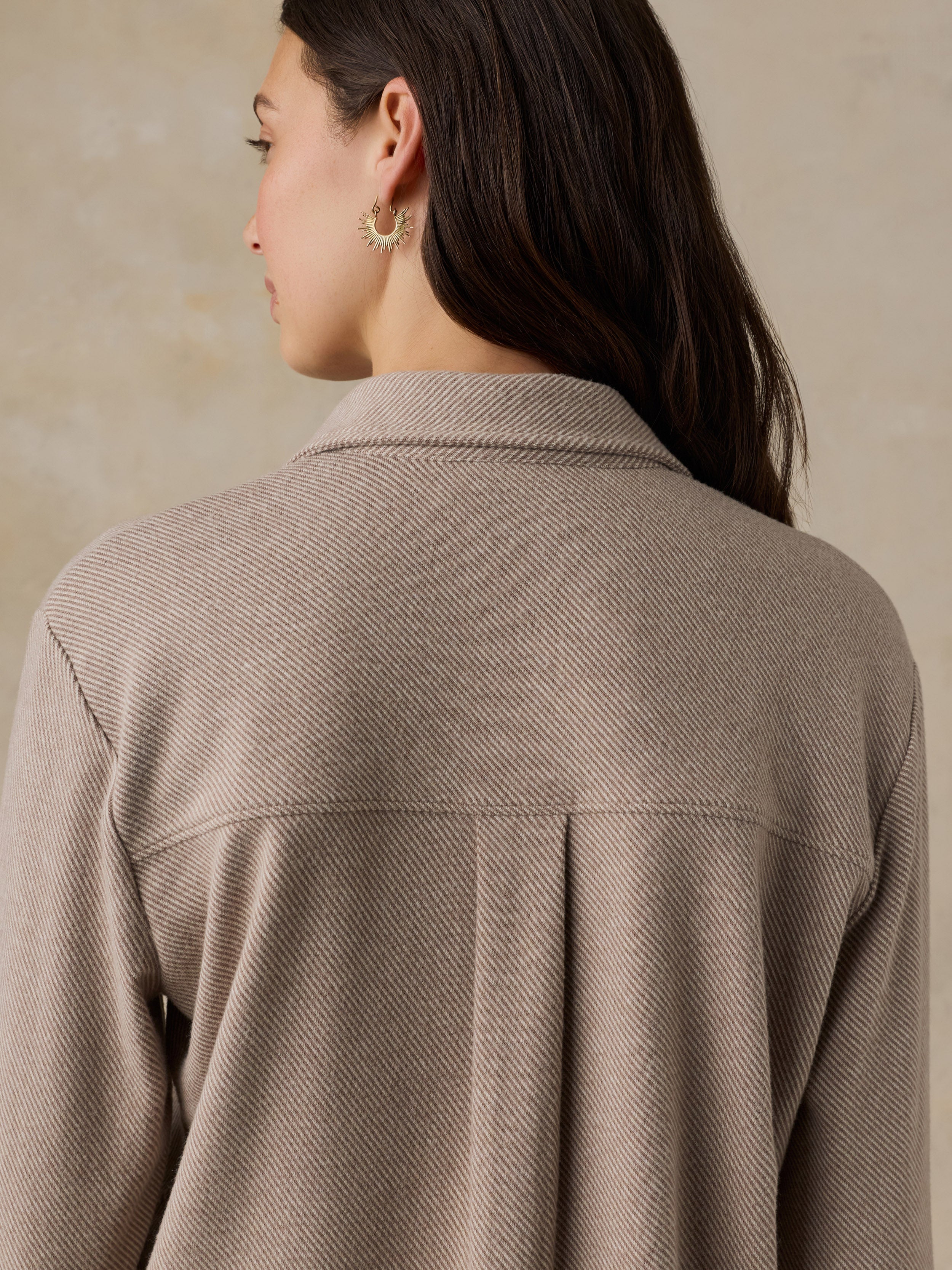 Woman wearing a beige button down shirt against a beige background