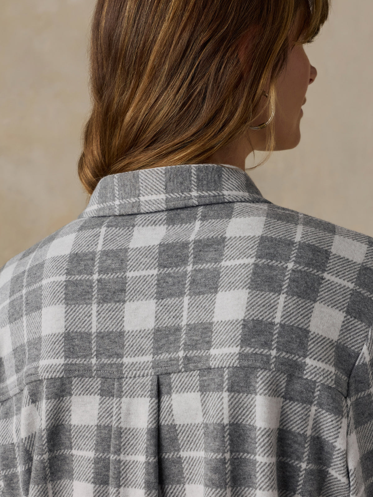 Woman wearing a grey plaid button down shirt against a beige background, image 6 of 6
