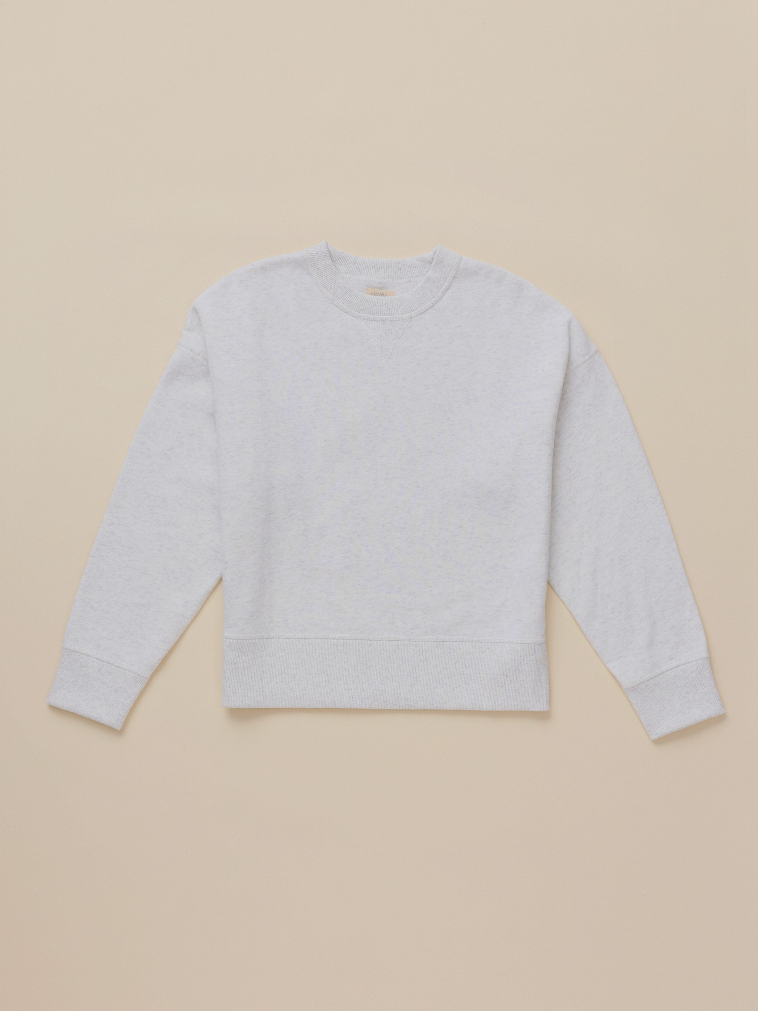 A light gray heather crewneck sweatshirt with long sleeves and ribbed cuffs and hem, laid flat against a solid beige background.