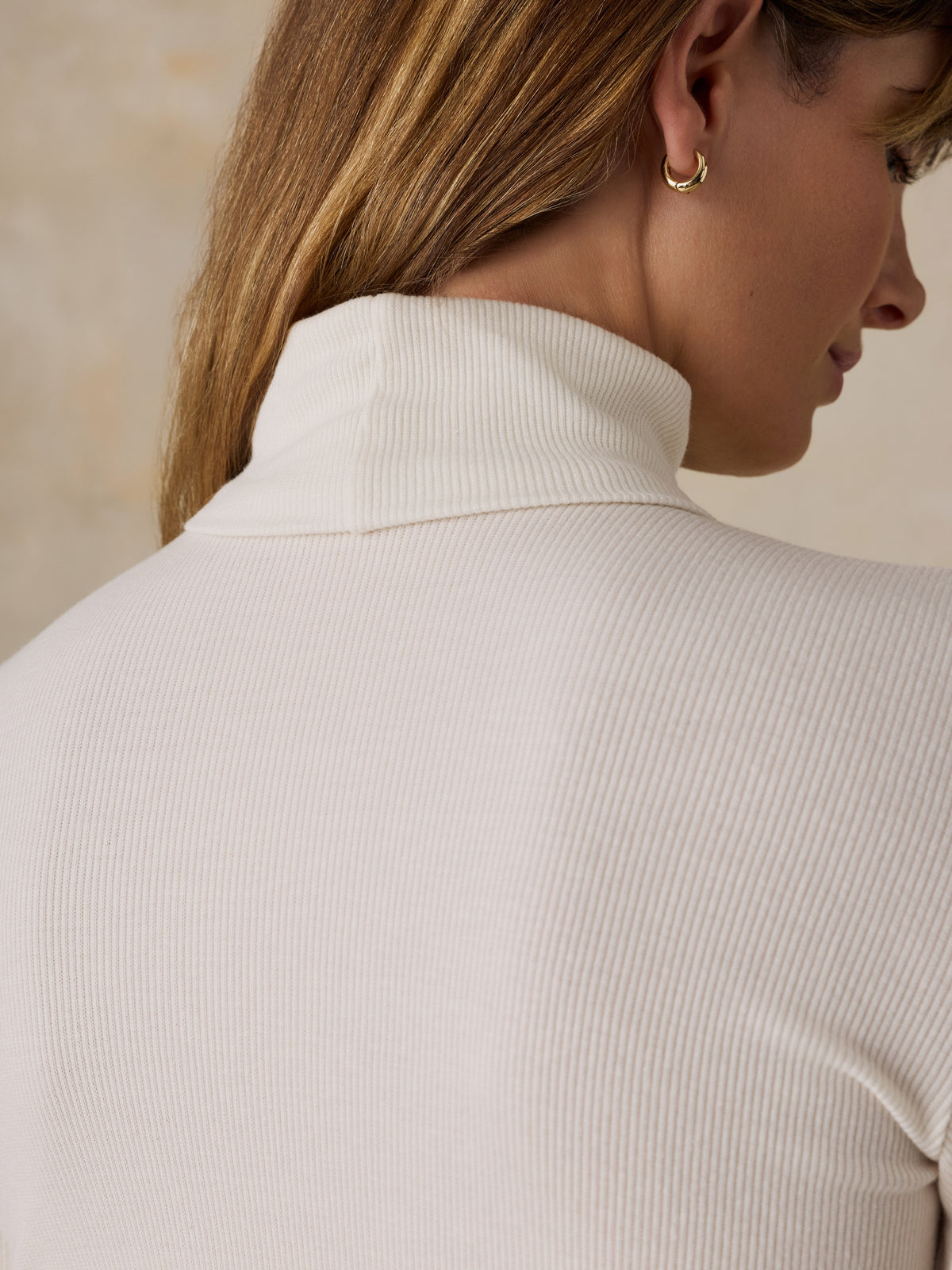 Close up of a woman viewed from behind wearing a white turtleneck, image 7 of 7