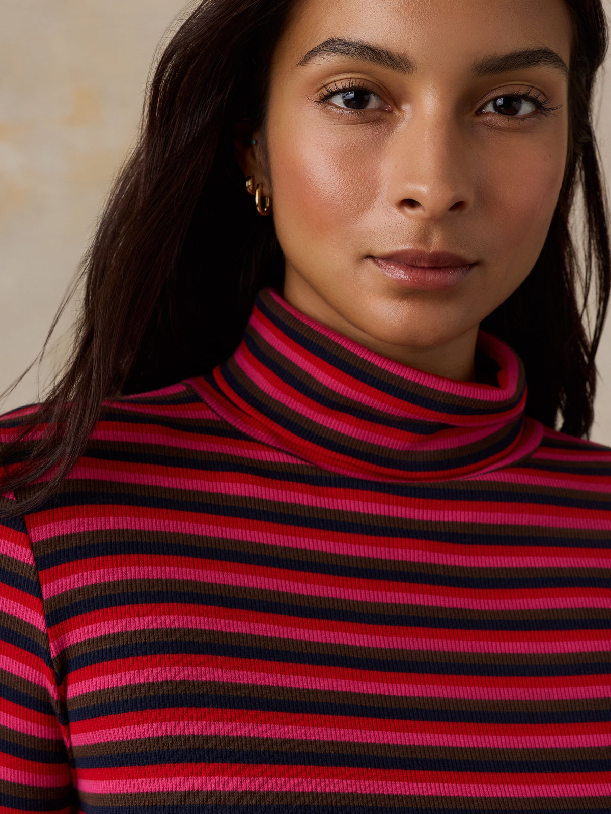Close up of a woman wearing a red striped turtleneck, image 2 of 6