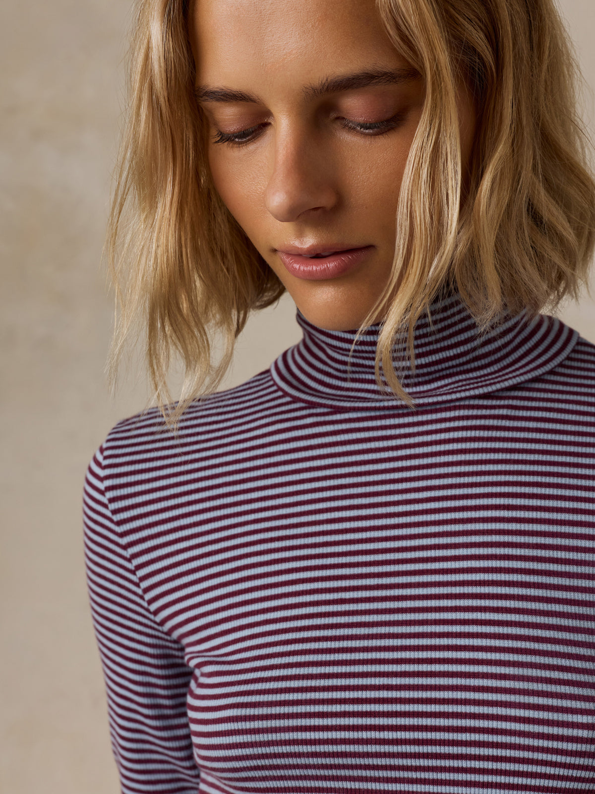 Close up of a woman wearing a blue striped turtleneck, image 3 of 6