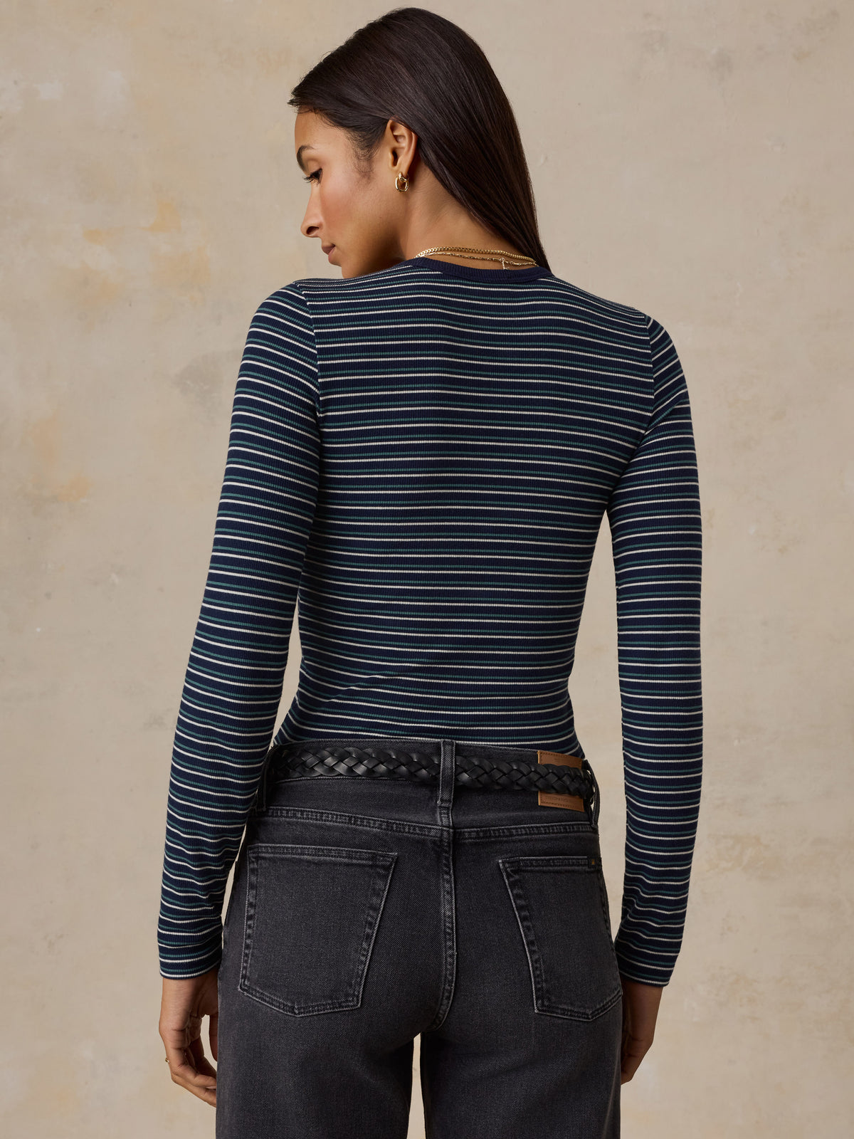 A woman viewed from behind wearing a blue striped shirt and jeans, image 4 of 6