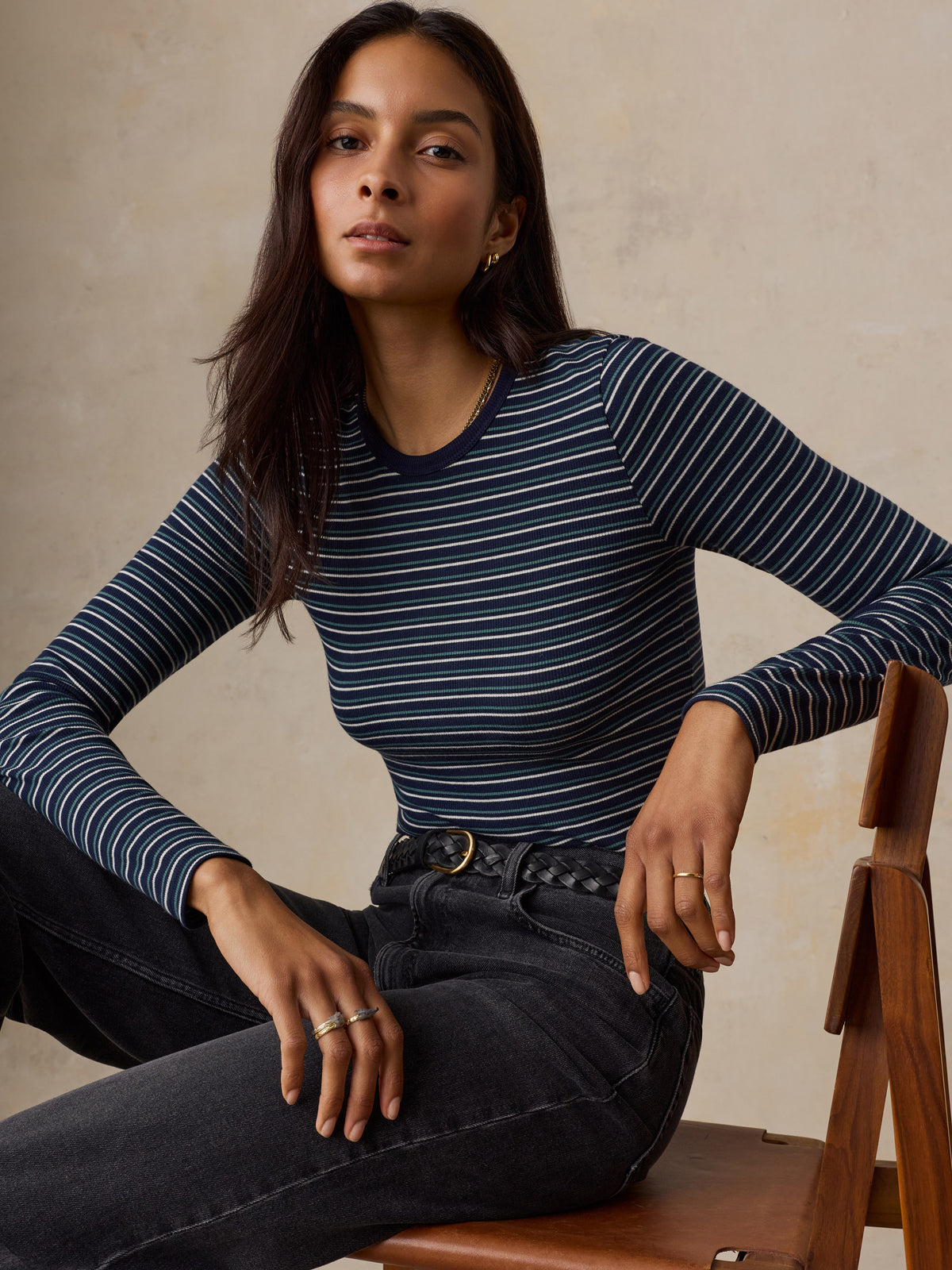 A woman wearing a blue striped shirt and jeans, image 5 of 6