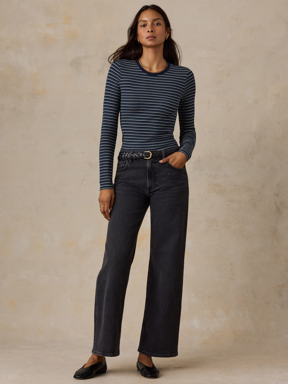 A woman wearing a blue striped shirt and jeans, image 2 of 6