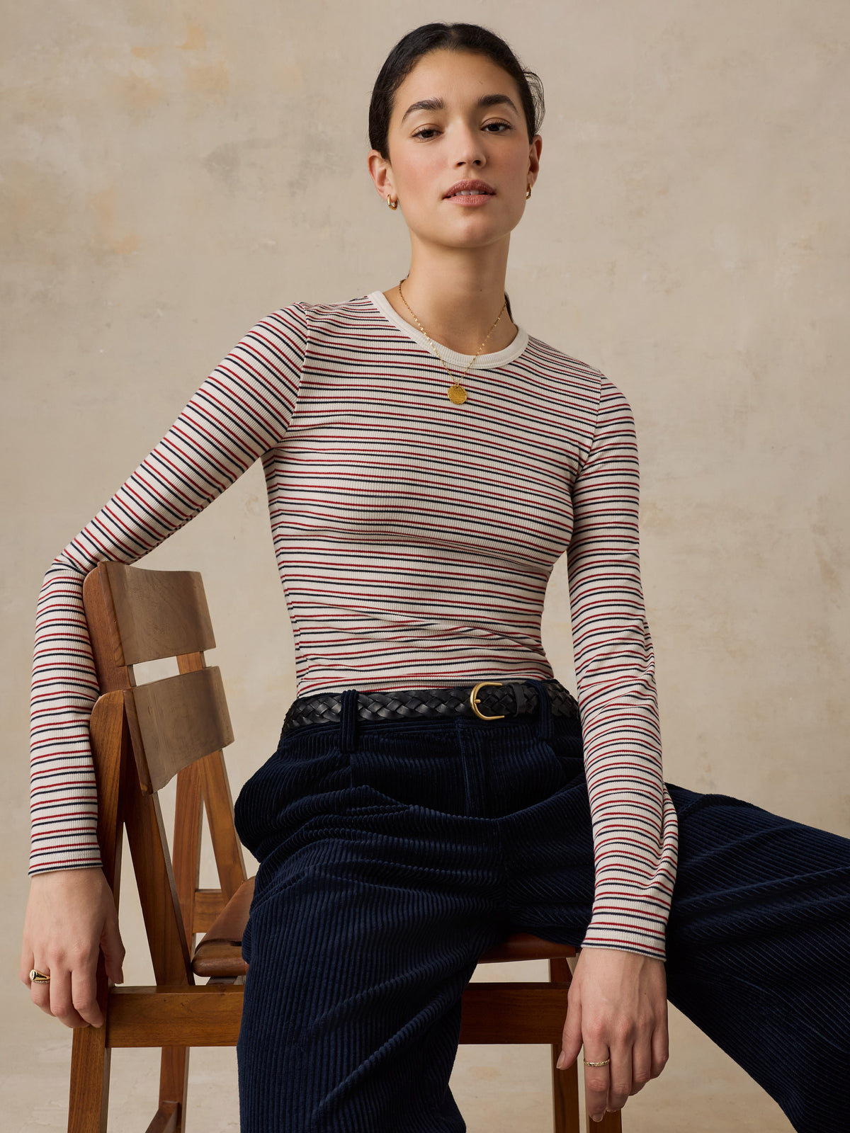A woman wearing a striped shirt and dark pants, image 4 of 6
