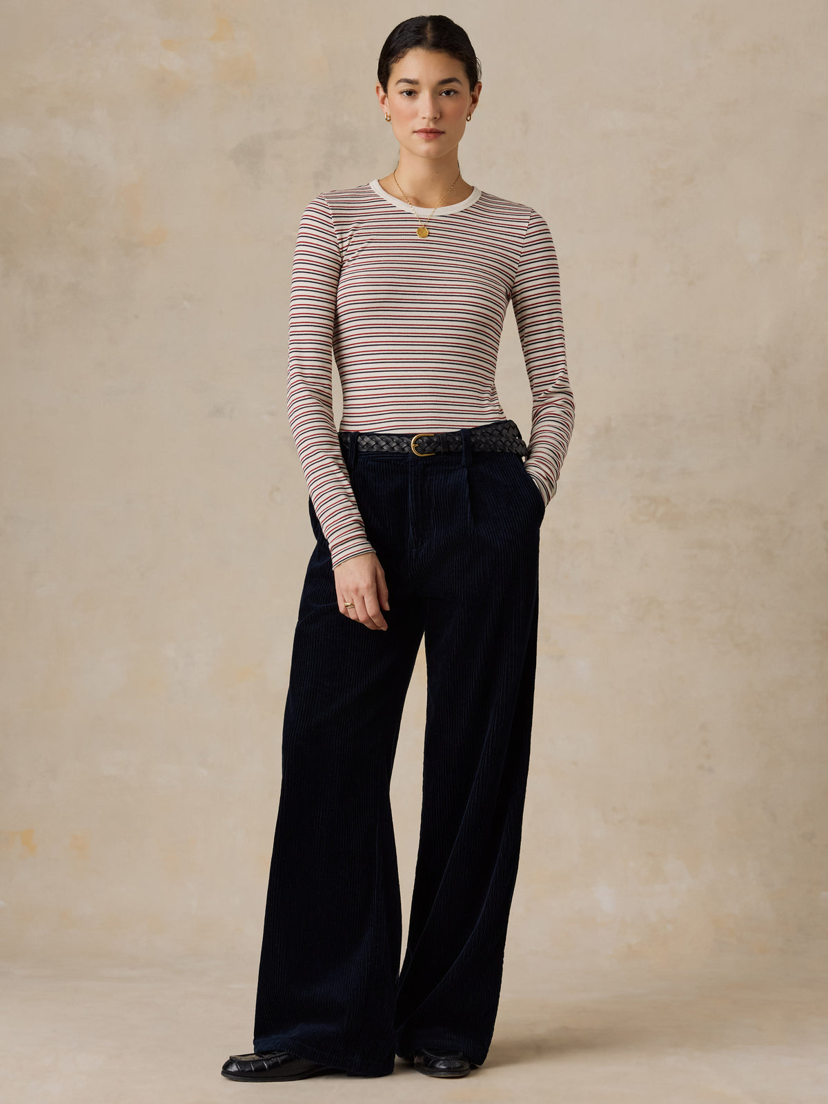 A woman wearing a striped shirt and dark pants, image 2 of 6