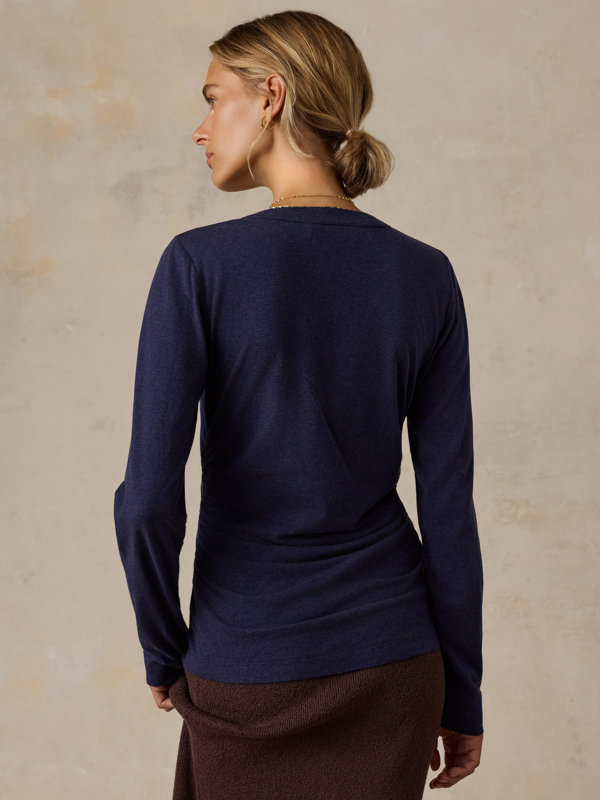 A woman wearing a blue long sleeve top and a brown skirt, image 4 of 6