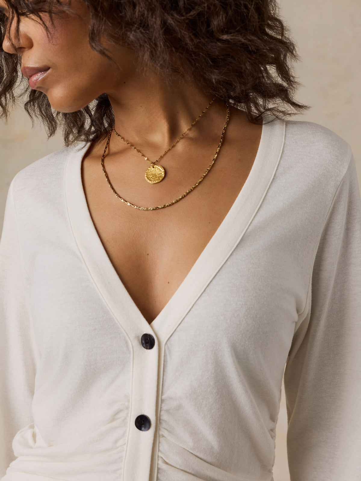 Close up of a woman wearing a white cardigan, image 3 of 6