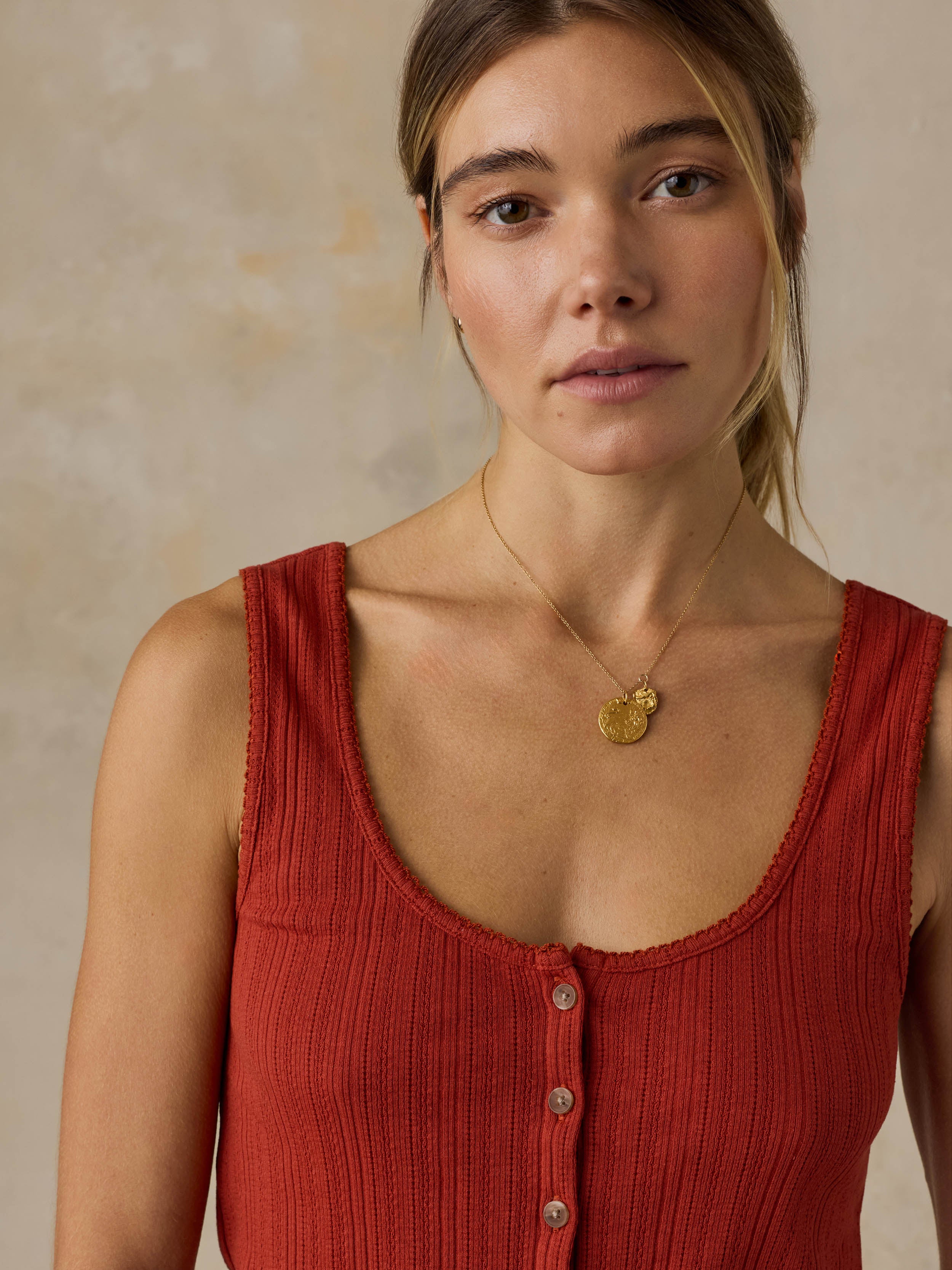 Woman wearing a red tank top against a beige background