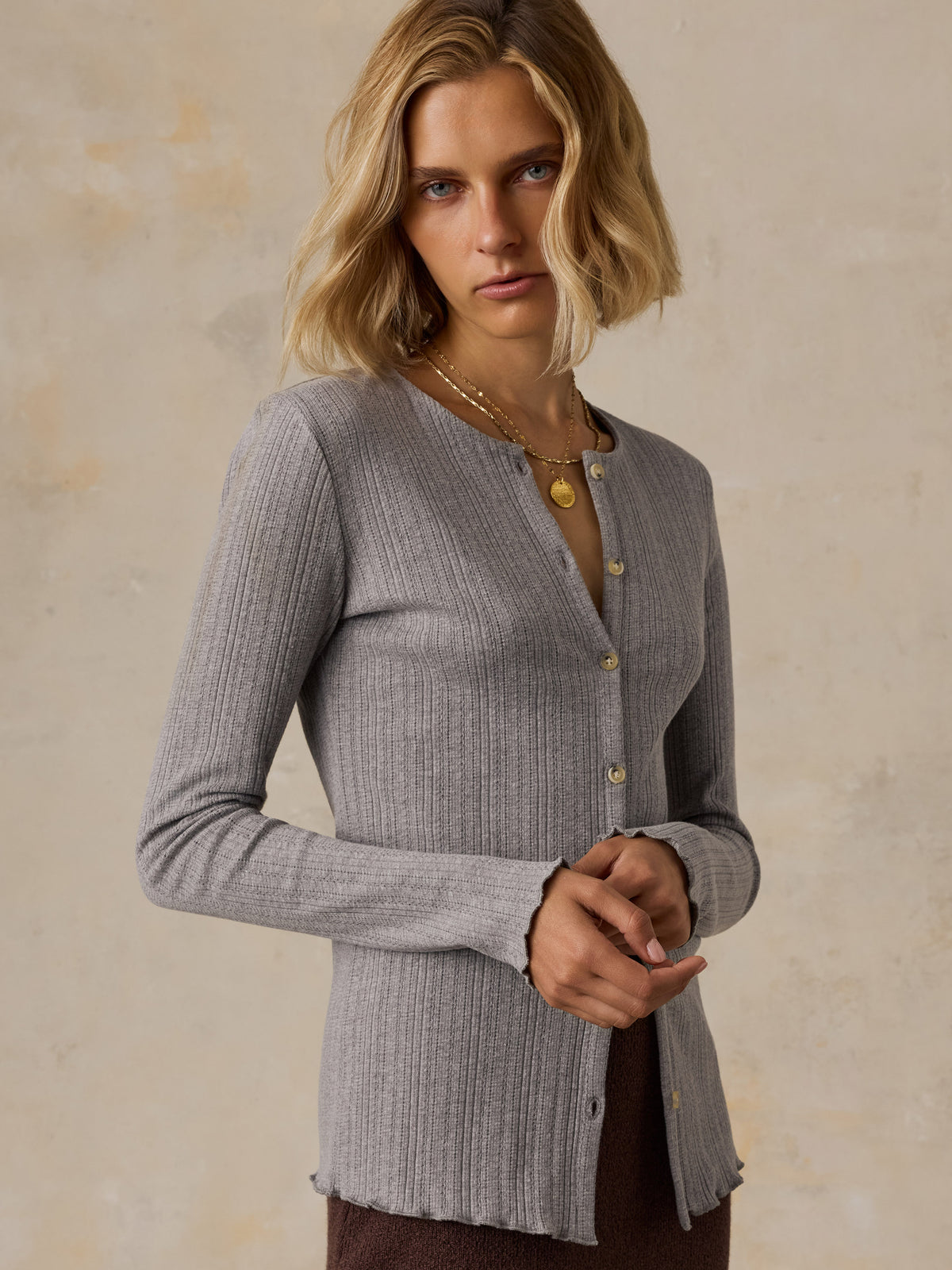 A woman wearing a grey cardigan and brown skirt, image 5 of 6