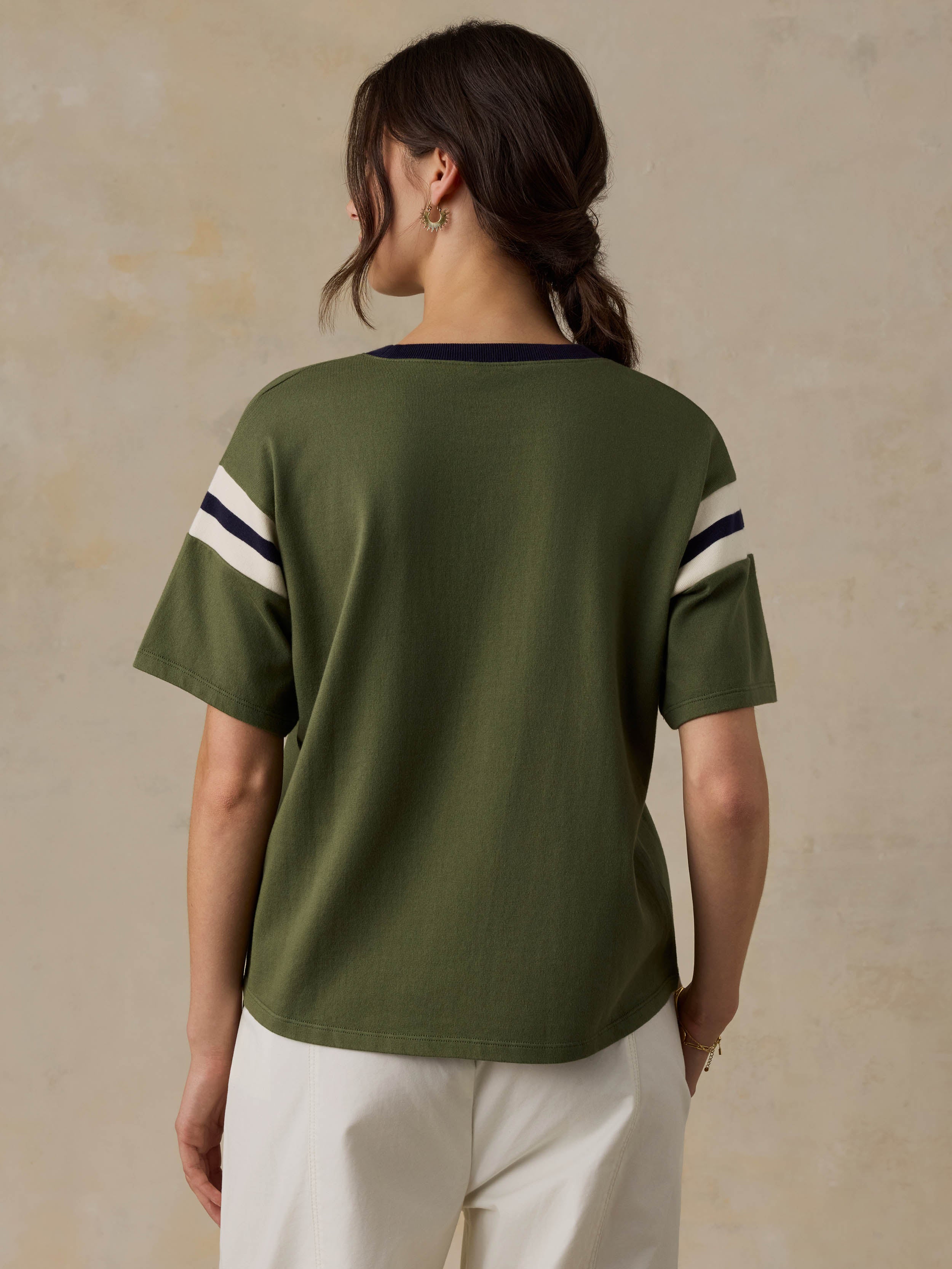Woman wearing a green t-shirt with white stripes on a beige background