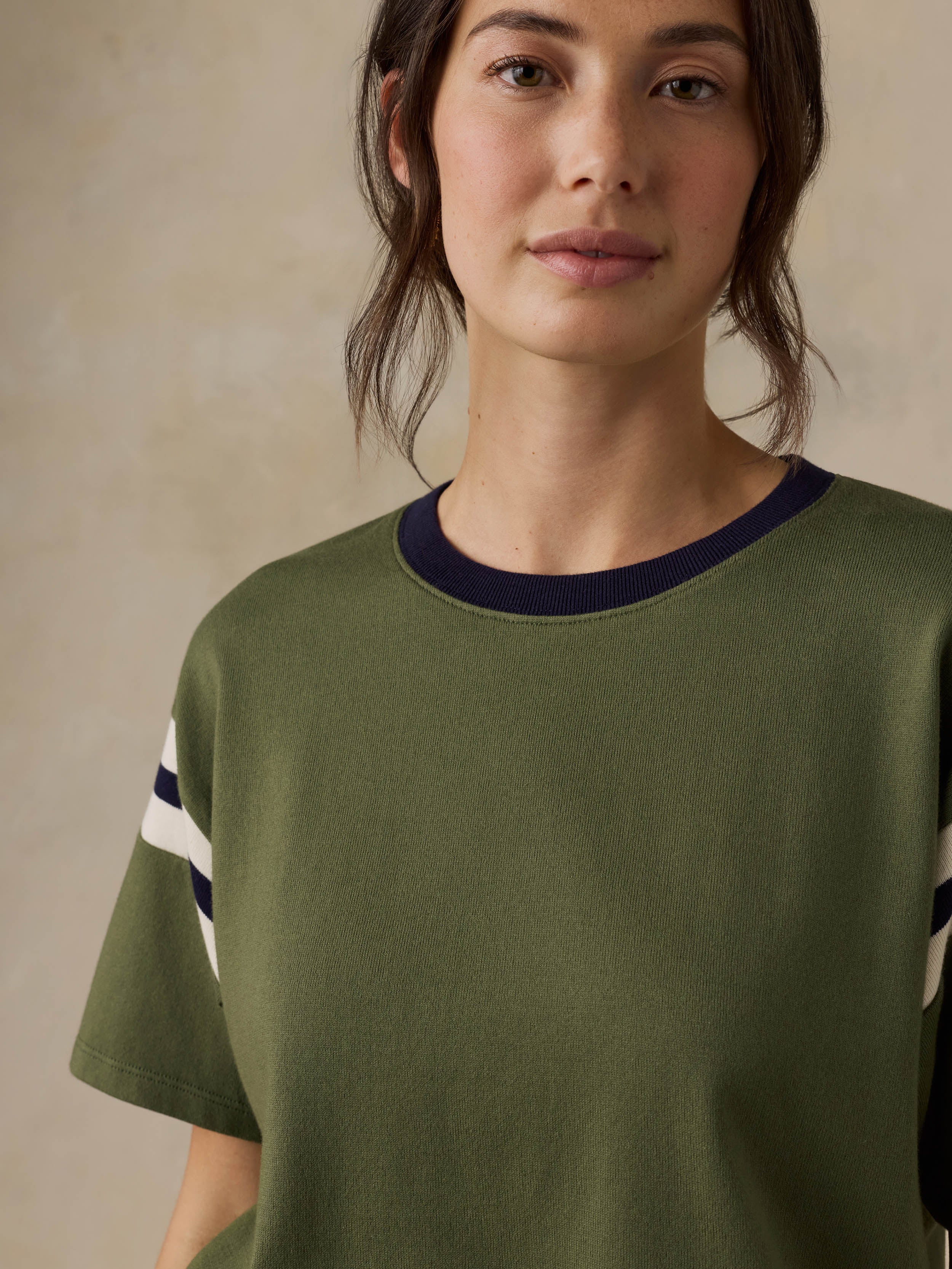 Woman wearing a green t-shirt with white stripes on a beige background
