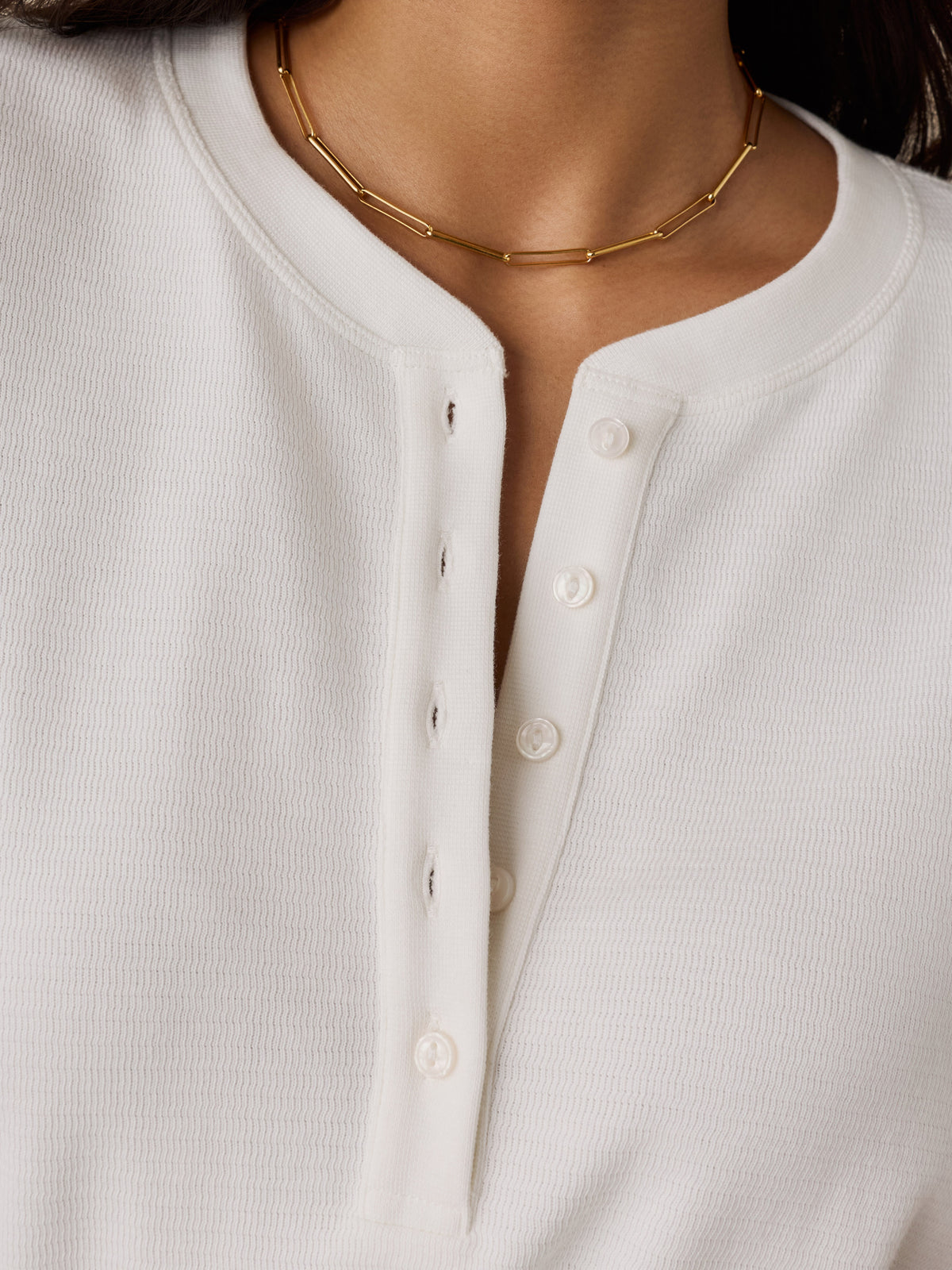 Close up of a woman wearing a white henley, image 3 of 6