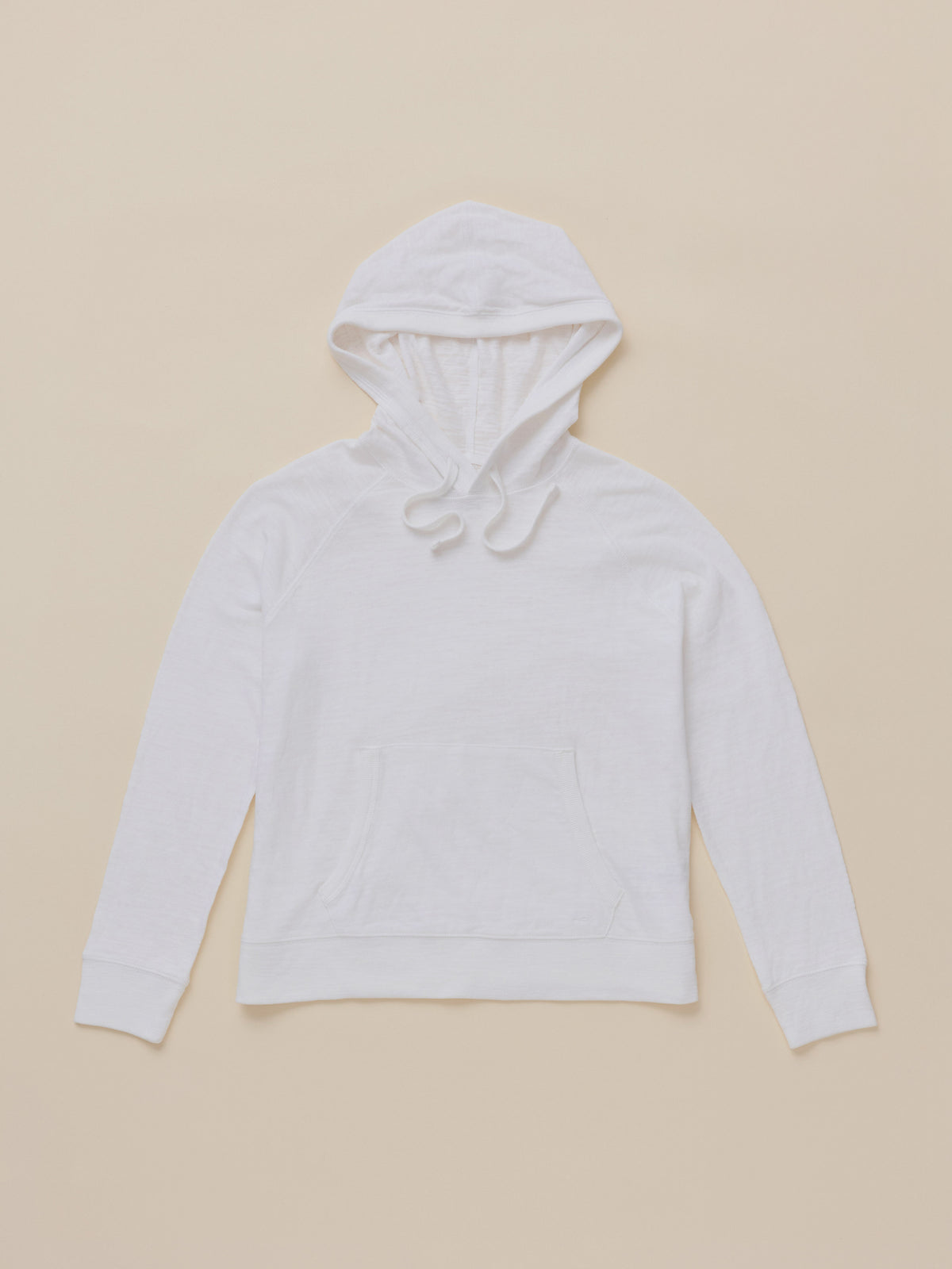 A plain white hoodie with a drawstring hood and front kangaroo pocket, laid flat against a solid beige background.