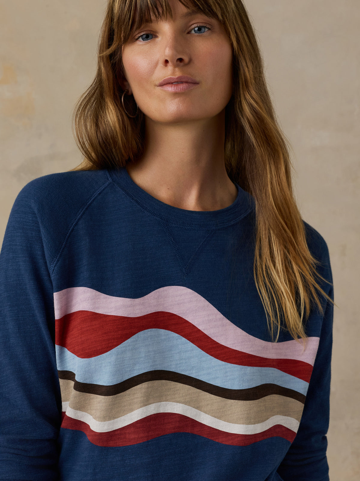 Woman wearing a navy blue and multicolor graphic crewneck against a beige background, image 6 of 6