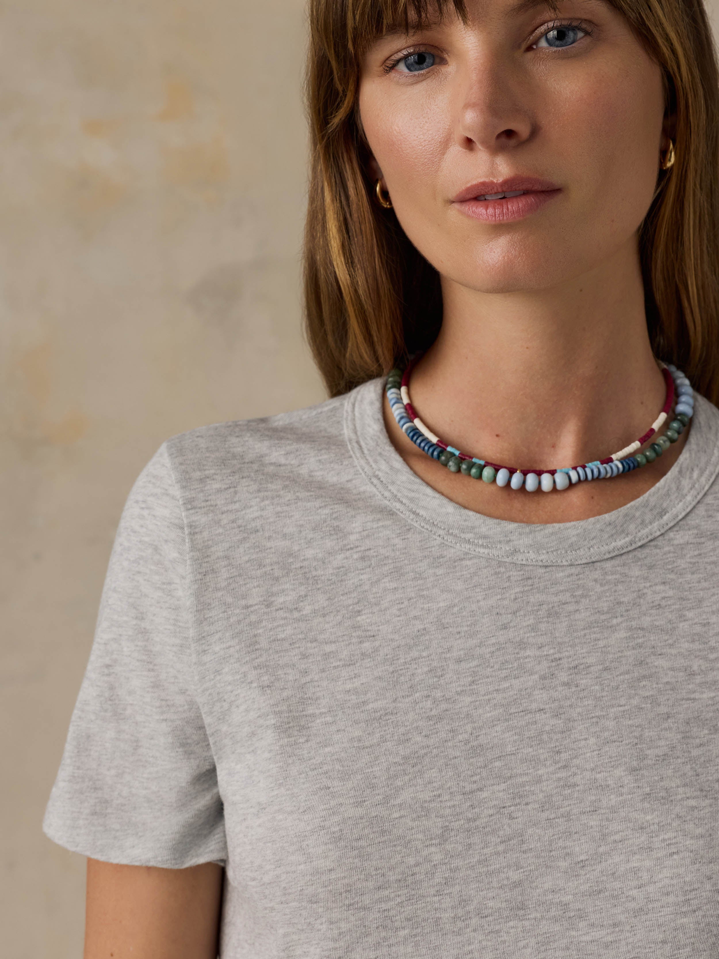 A woman wearing a grey t-shirt against a beige background
