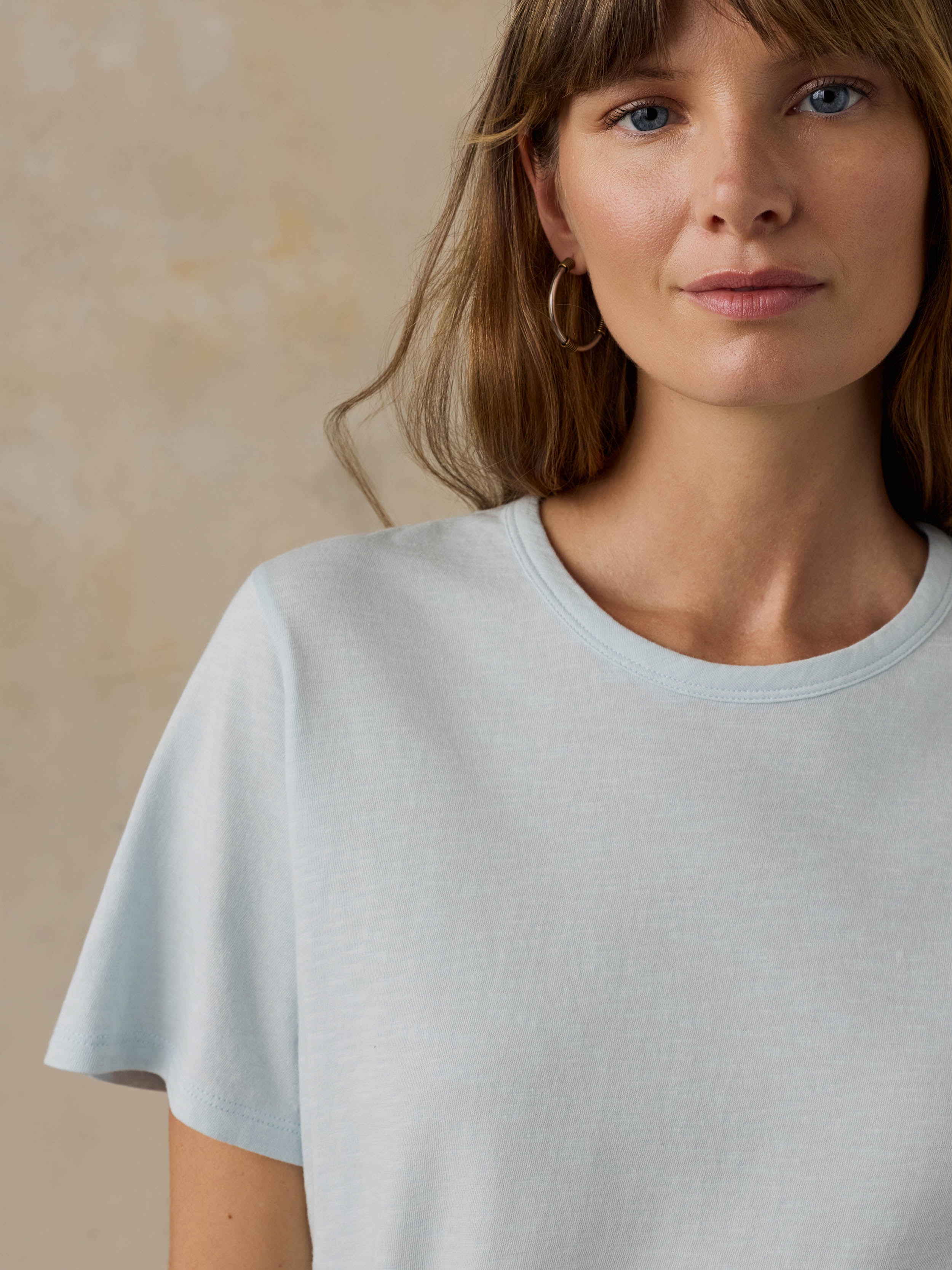 Woman wearing a light blue t-shirt against a beige background