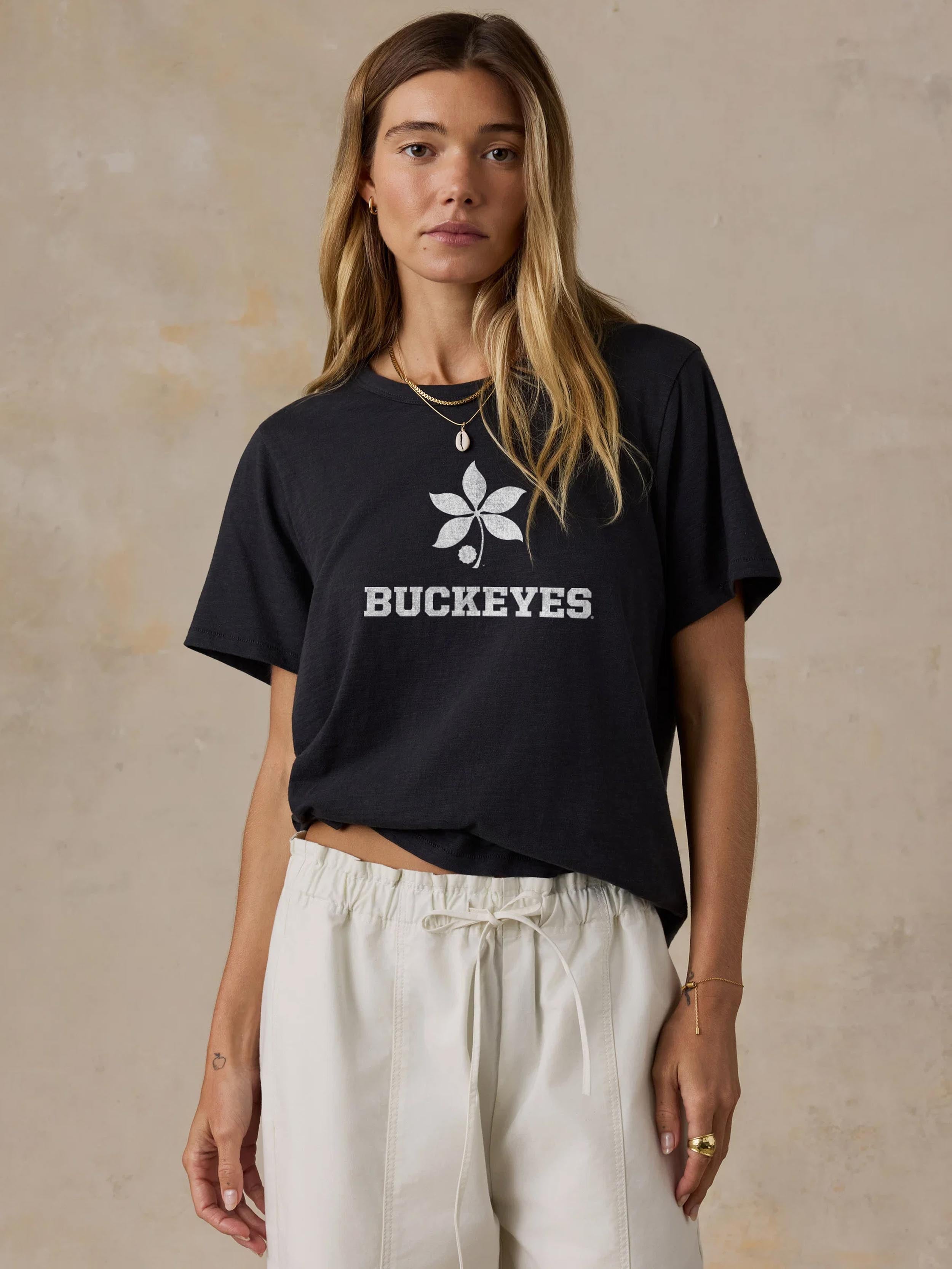 A woman wearing a black Ohio State tee and white pants