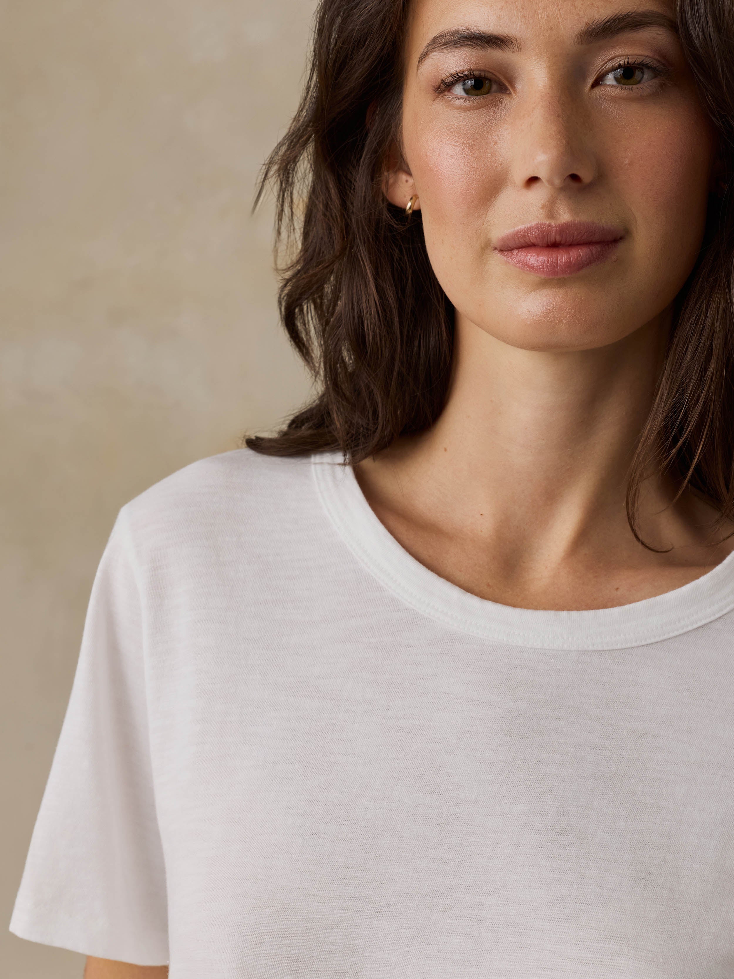 Woman wearing a white t-shirt against a beige background