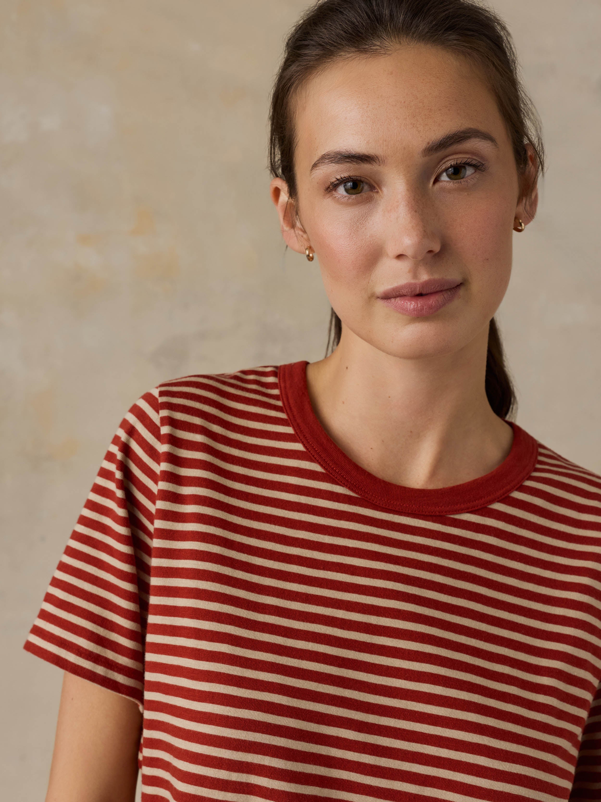 Woman wearing a red striped shirt against a beige background