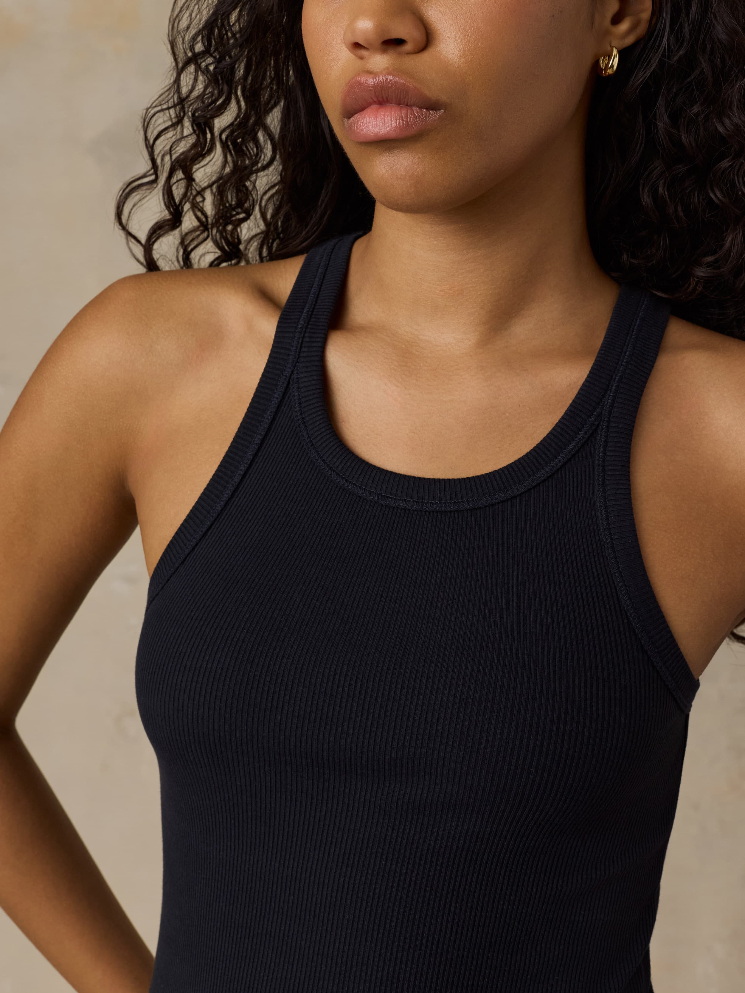 Woman wearing a black tank top against a beige background