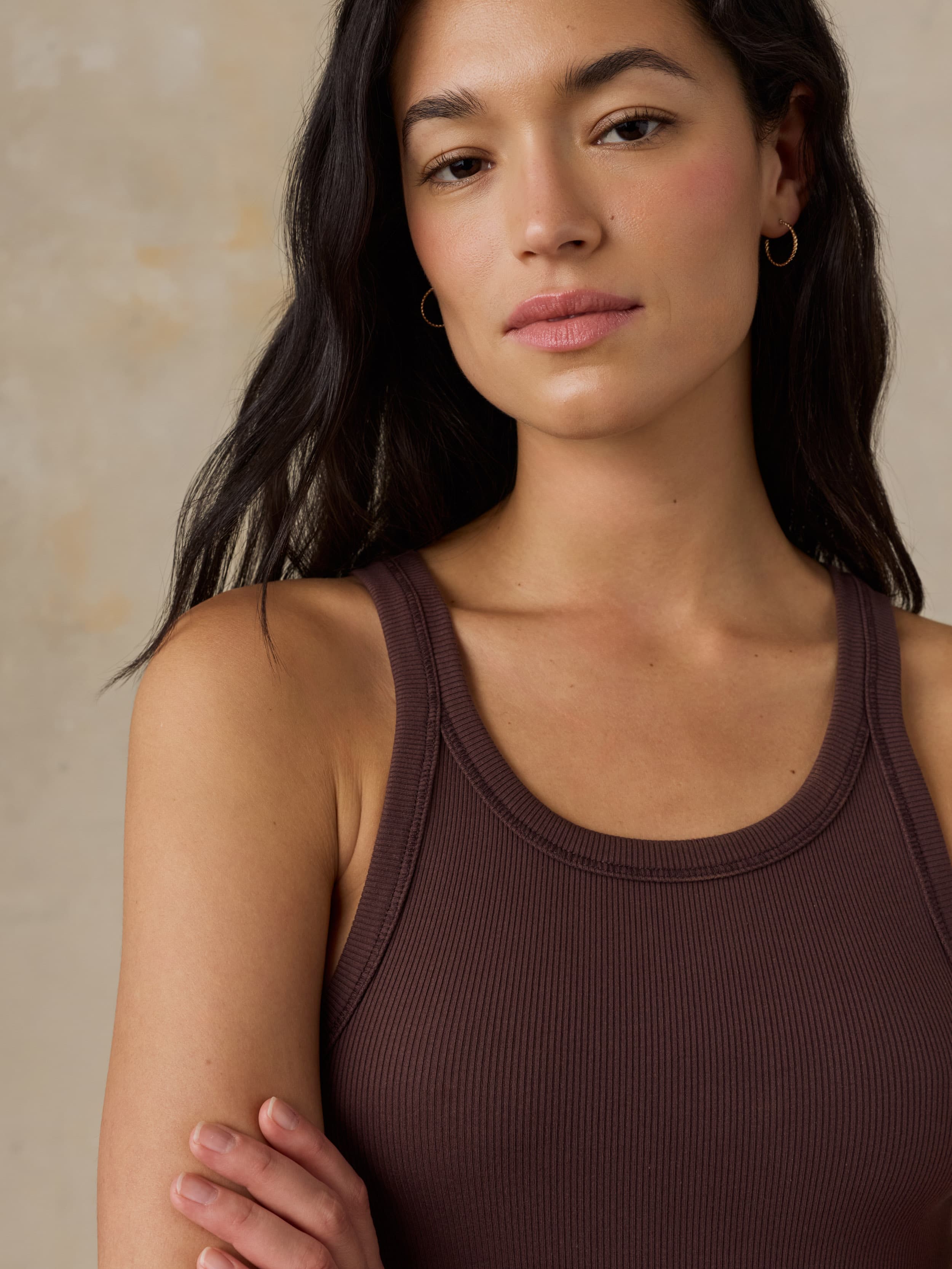Woman wearing a brown tank top against a beige background