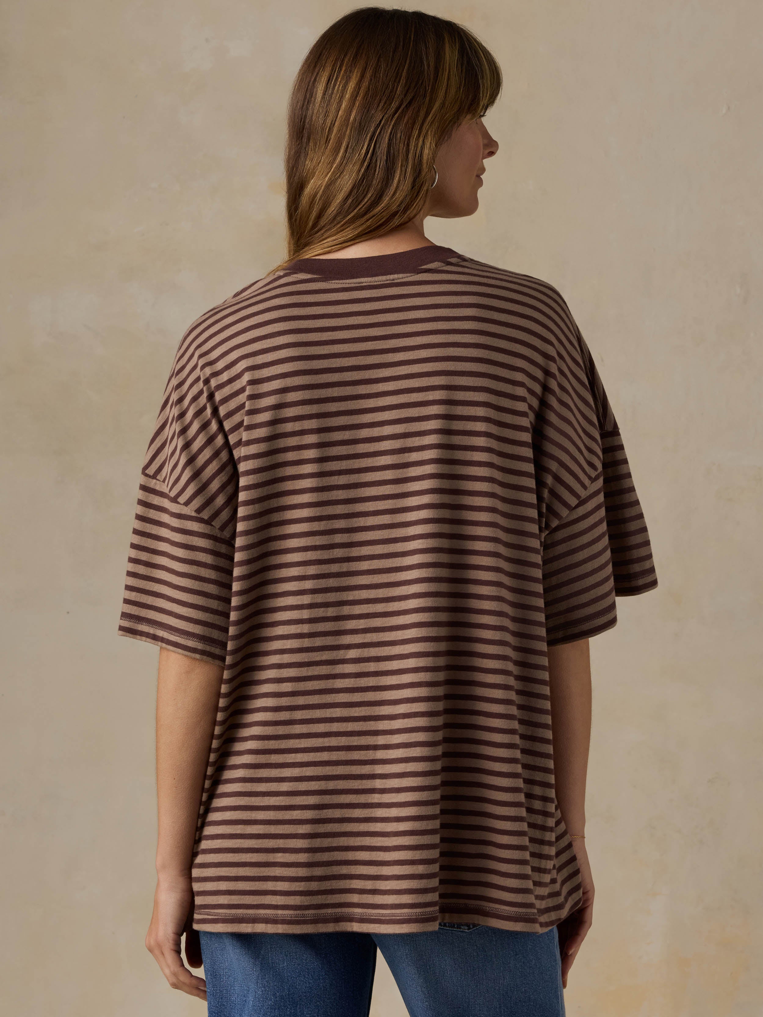 Person wearing a brown striped shirt against a beige background