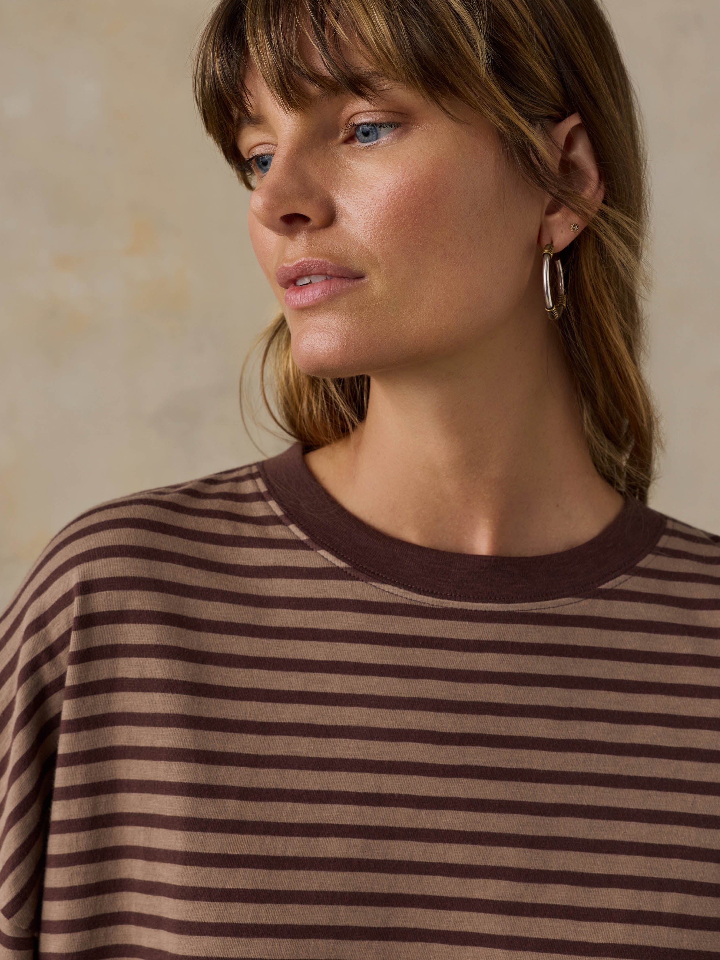 Woman wearing a brown striped sweater against a neutral background