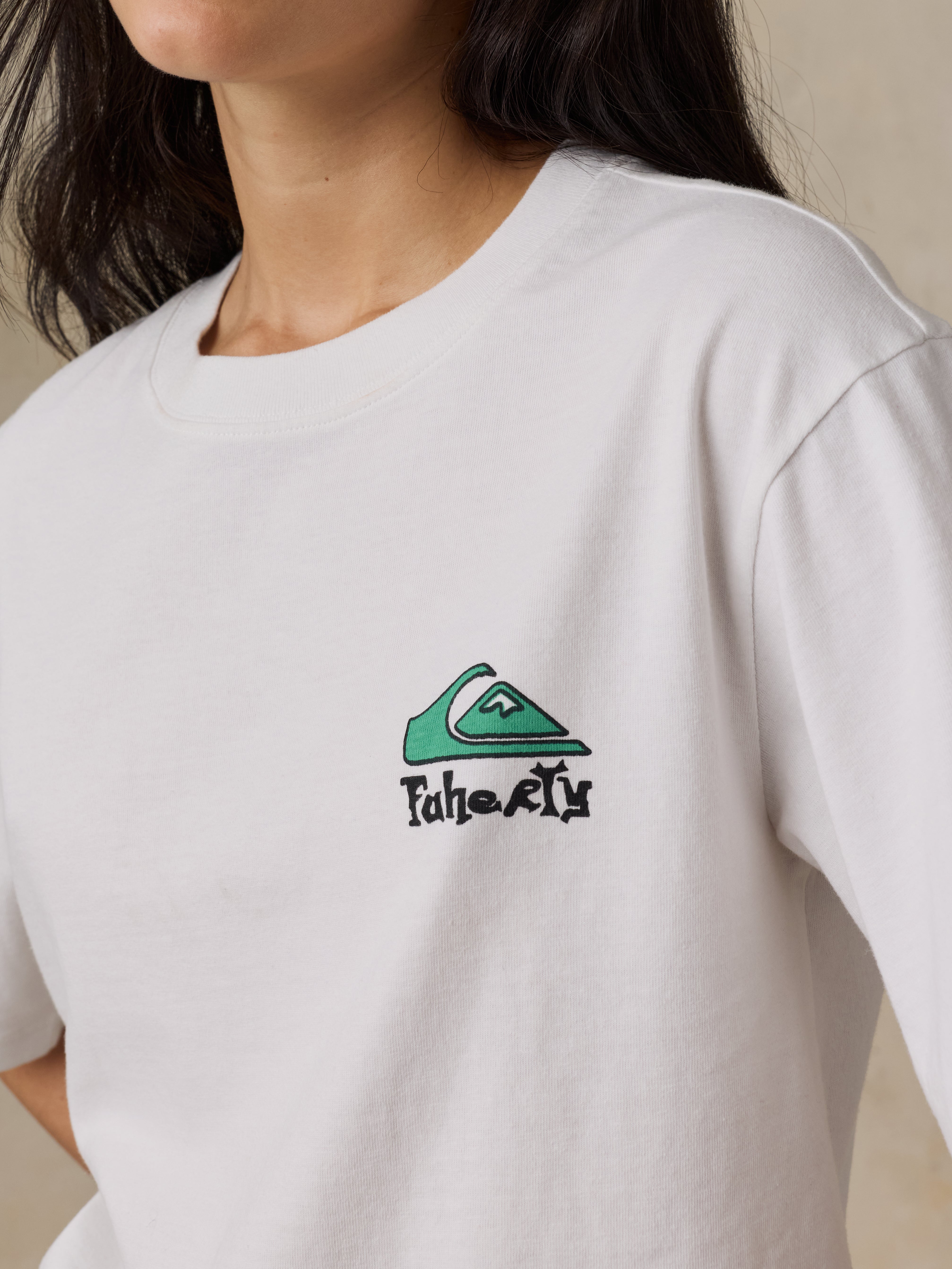 White t-shirt with a green and black logo on a neutral background