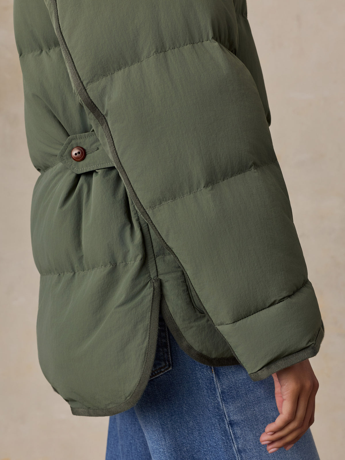 Close up of a woman wearing a green jacket and blue jeans, image 5 of 7