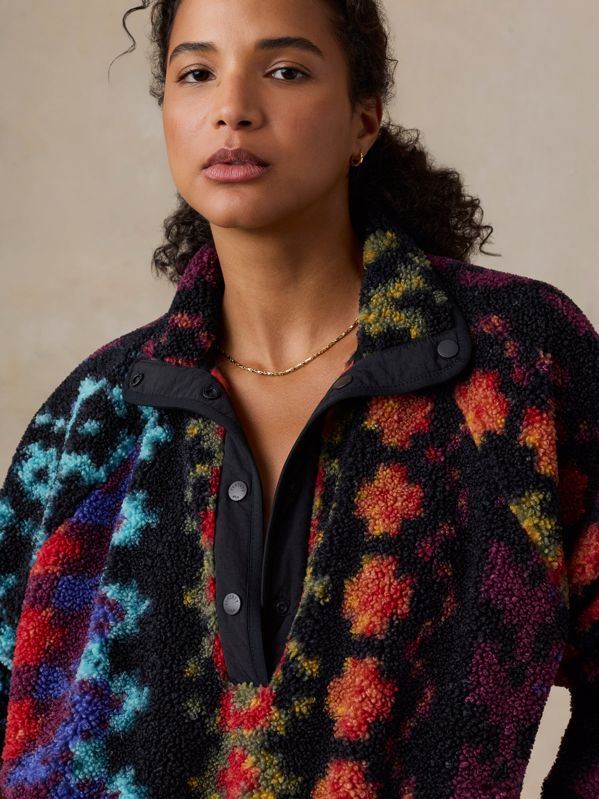 A close up of a woman wearing a colorful, patterned fleece pullover , image 6 of 7