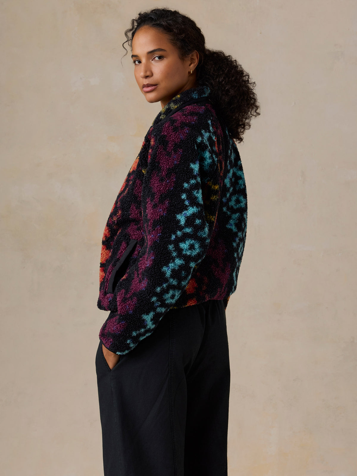 A woman wearing a colorful, patterned fleece pullover and black drawstring pants, image 7 of 7