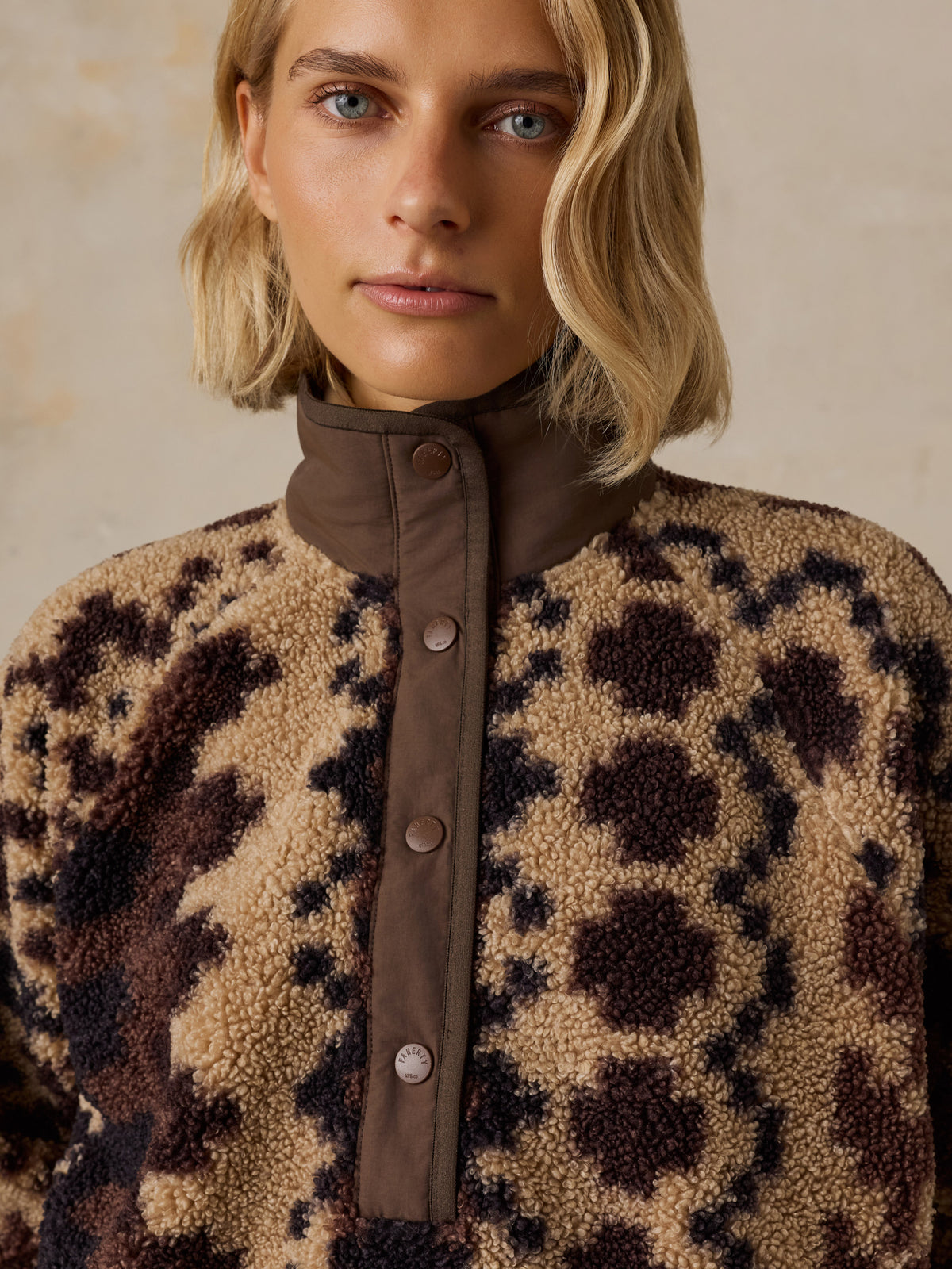 Close up of a woman wearing a brown printed fleece jacket, image 5 of 5