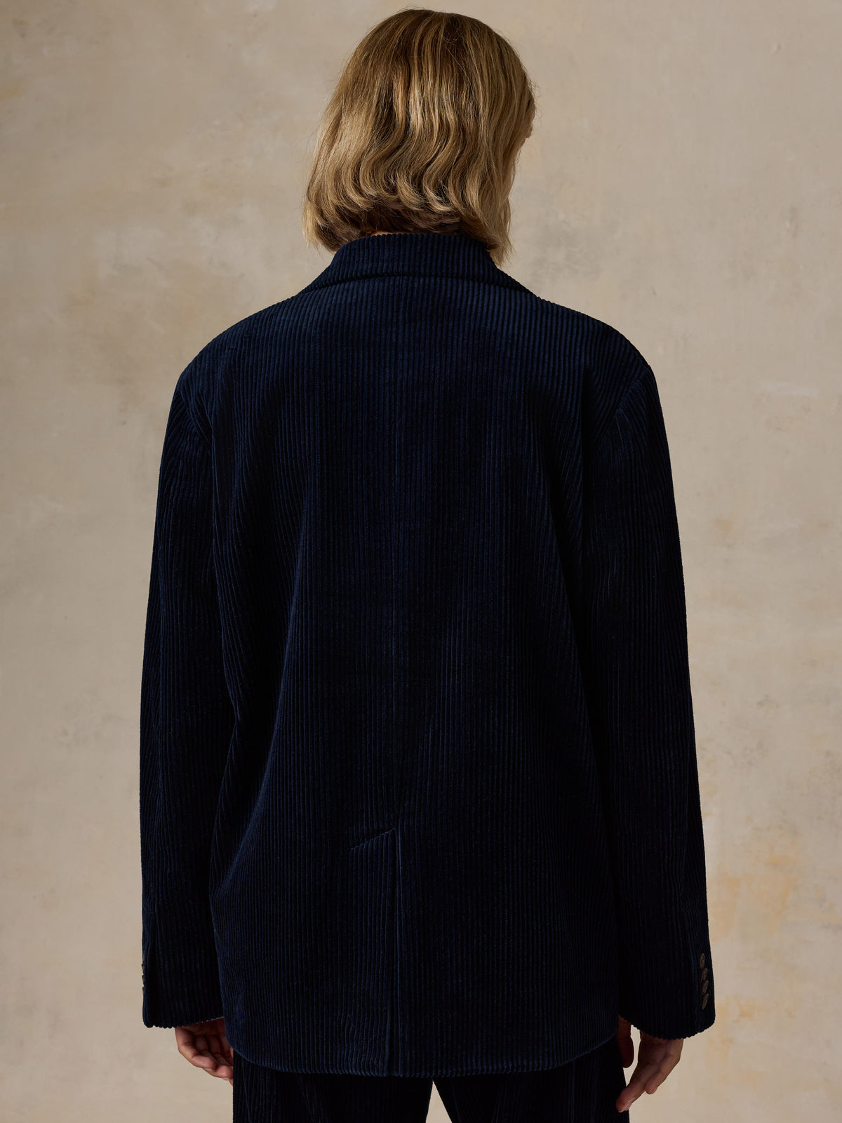 A woman wearing a dark navy blazer and matching pants viewed from behind, image 2 of 7
