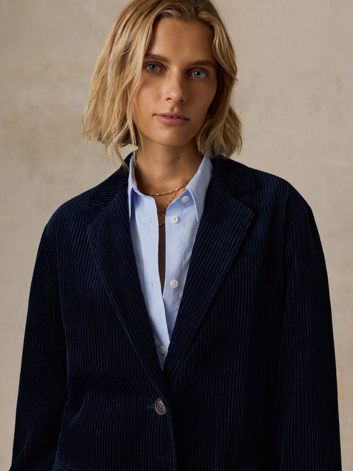 Close up of a woman wearing a dark navy corduroy blazer over a light blue shirt, image 4 of 7