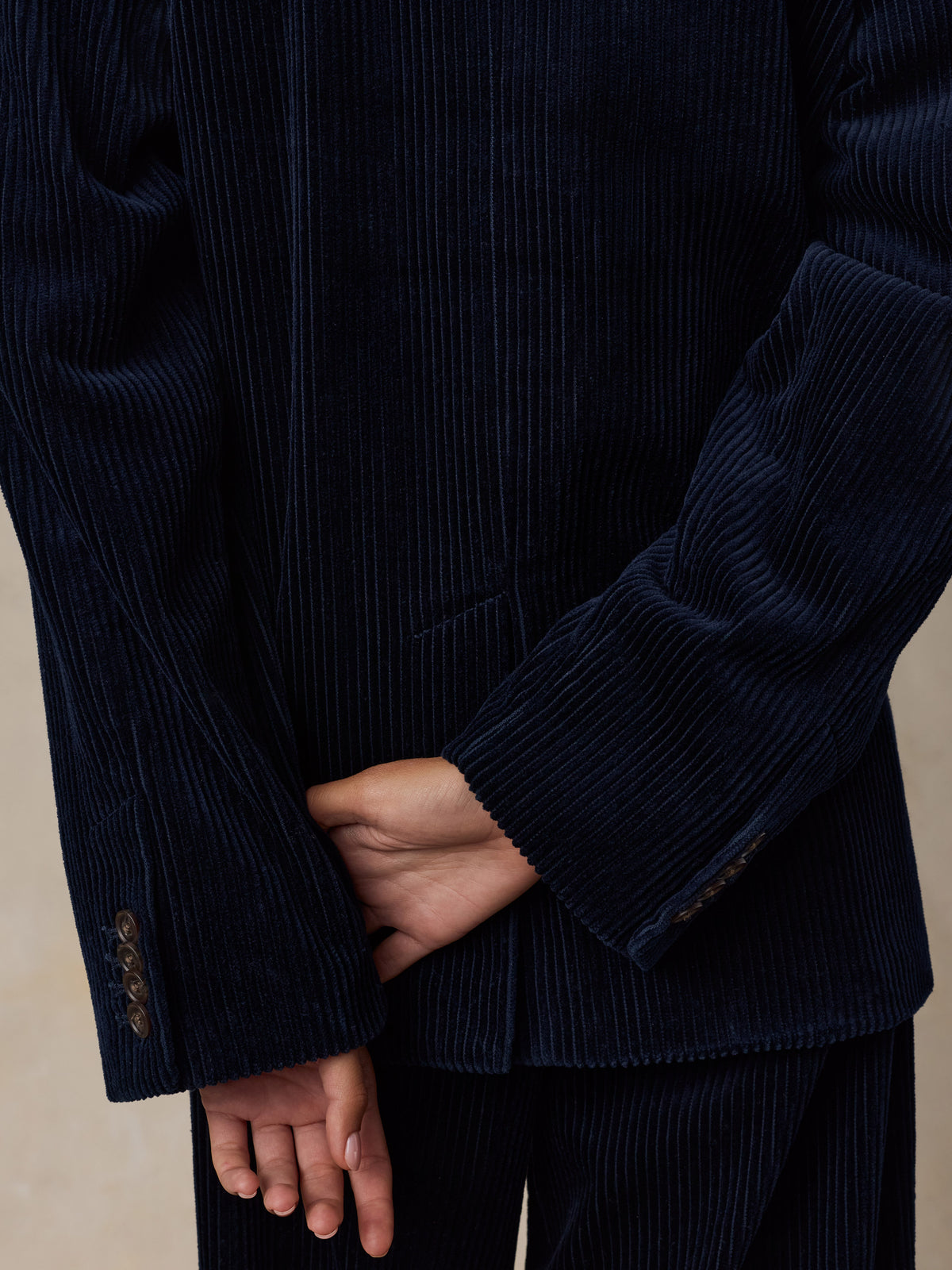 Close up of a woman viewed from behind wearing a dark navy blue corduroy suit, image 5 of 7