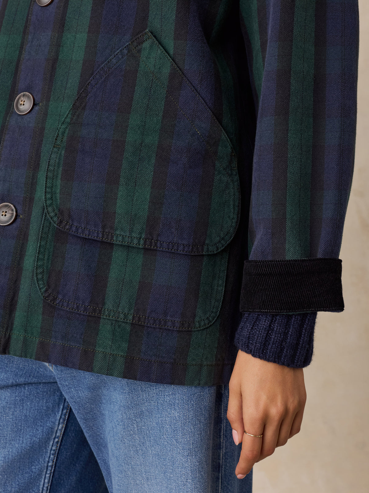 Close up of a woman wearing a green plaid jacket and jeans, image 5 of 6