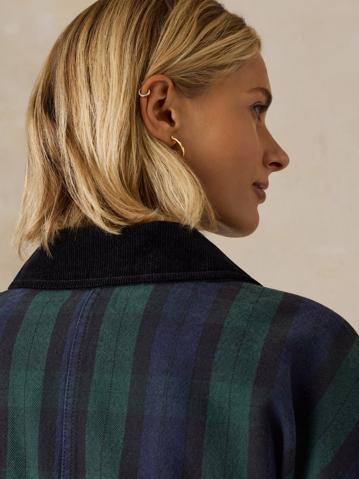 Close up of a woman viewed from behind wearing a green plaid jacket, image 6 of 6