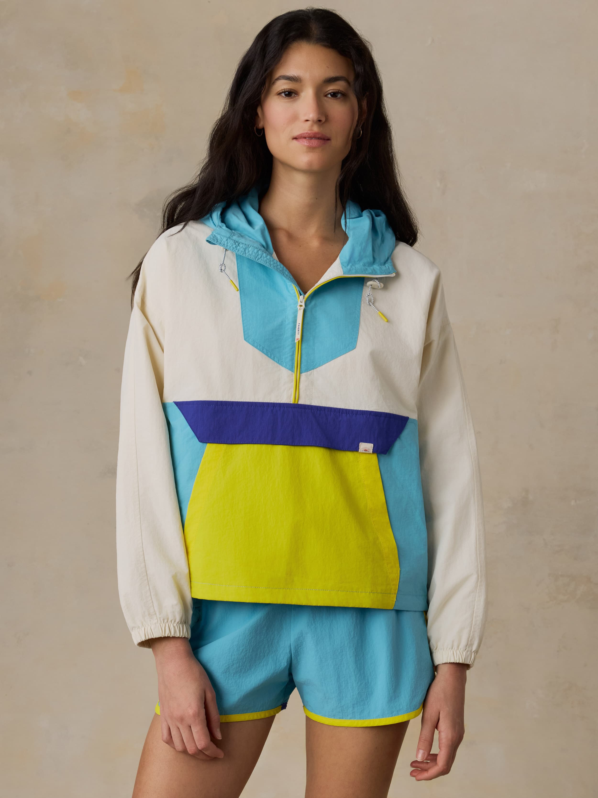 Woman wearing a colorful windbreaker jacket against a beige background