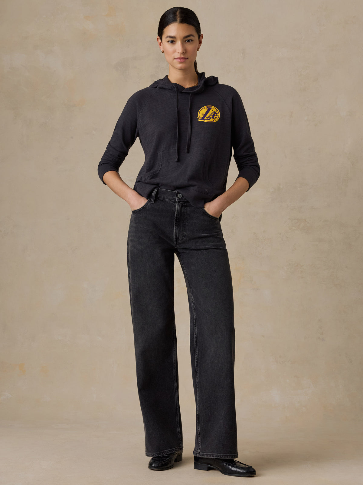 A woman wearing a black LA Lakers hoodie and jeans, image 5 of 5