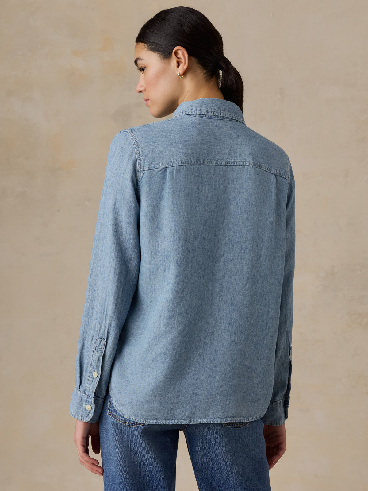 A woman viewed from behind wearing a LA Lakers chambray shirt and jeans, image 2 of 6