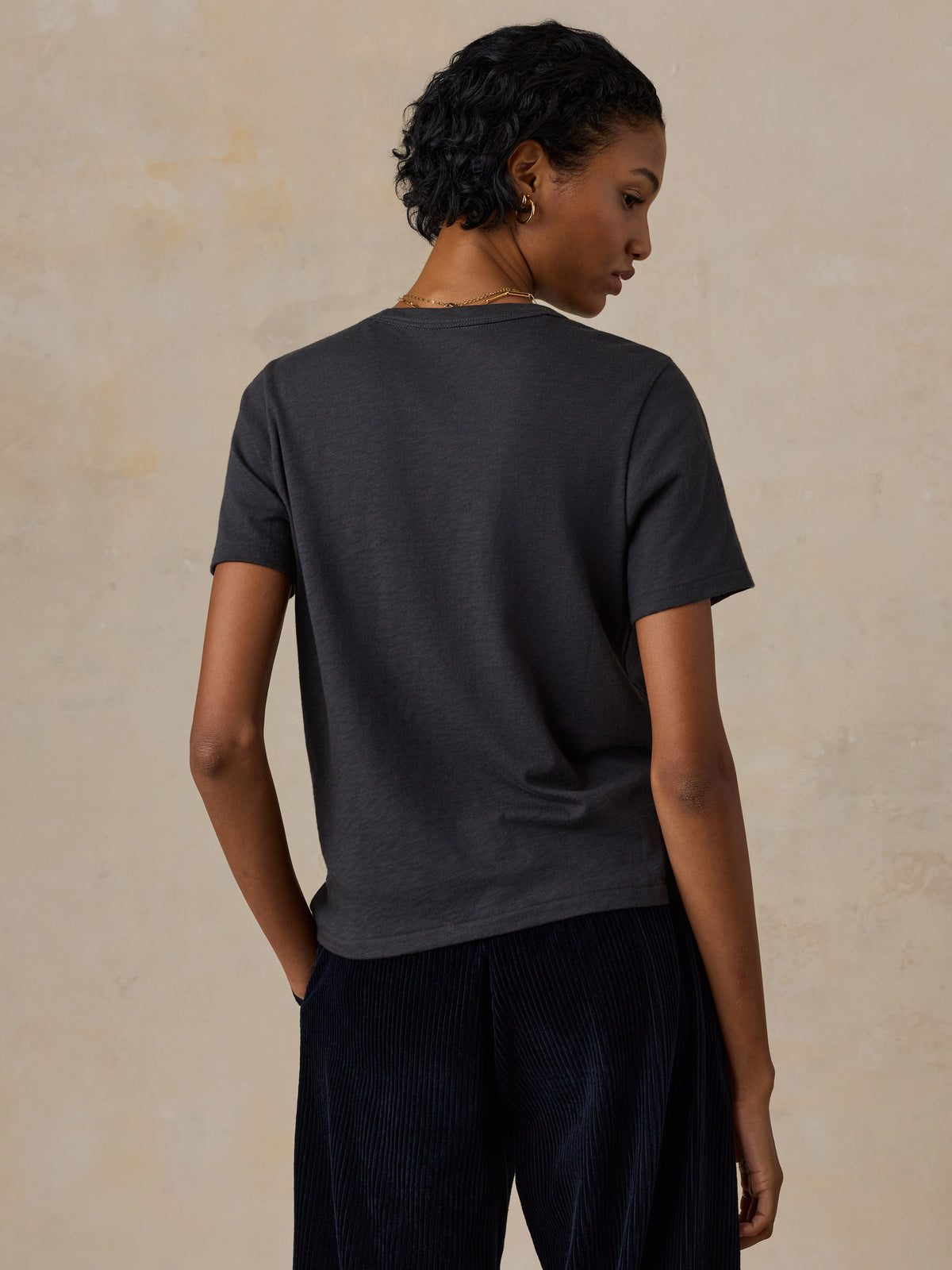A woman viewed from behind wearing a black Boston Celtics tee, image 4 of 6
