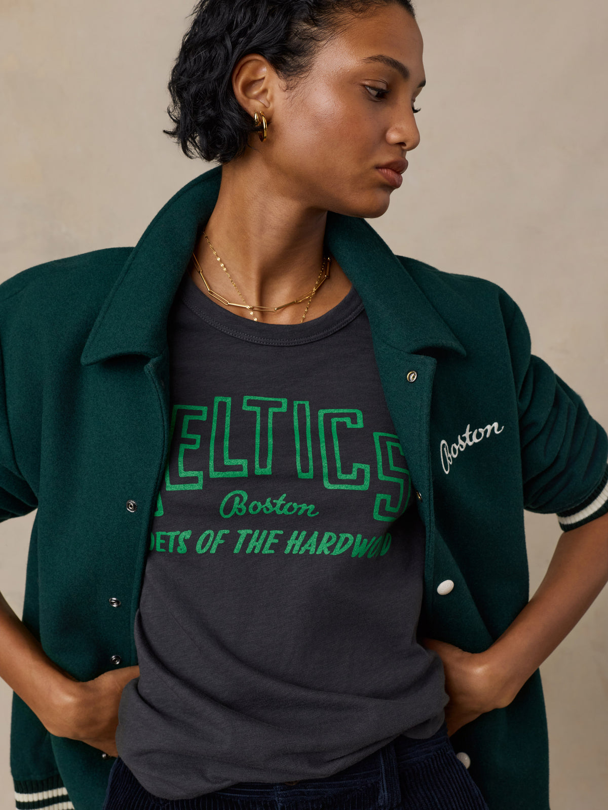 Close up of a woman wearing a black Boston Celtics tee and a varsity jacket, image 6 of 6
