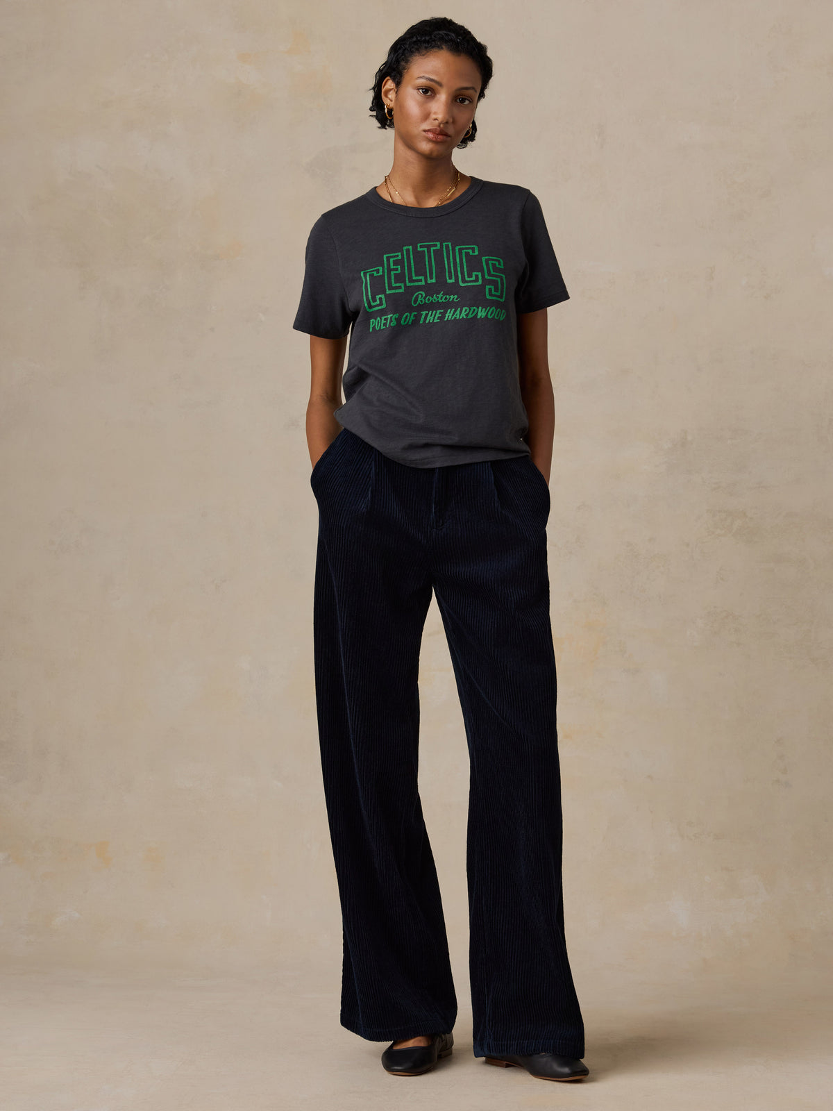 A woman wearing a black Boston Celtics tee and navy pants, image 5 of 6