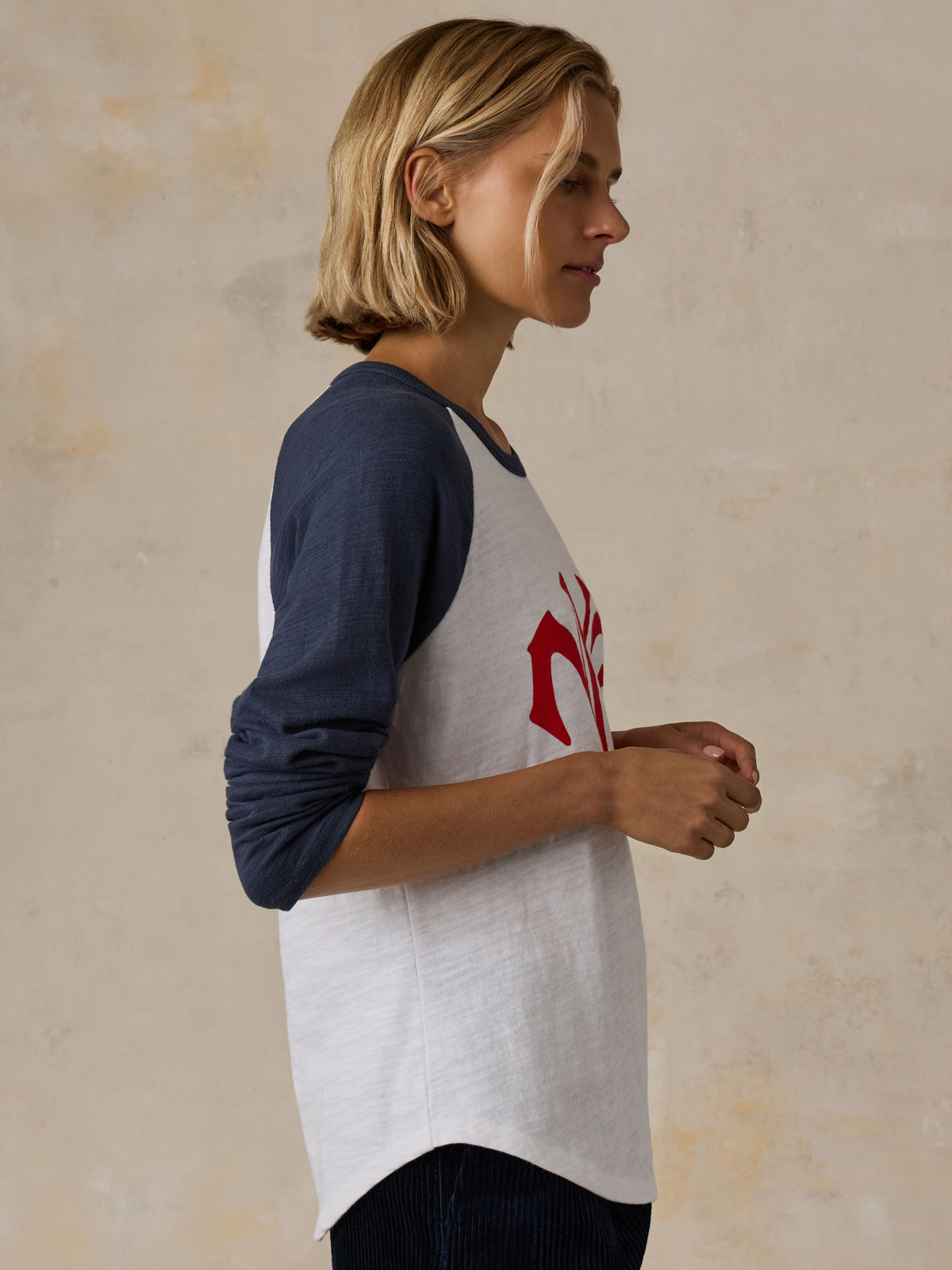 A woman wearing a white and blue NY Giants baseball tee with navy pants, image 4 of 5