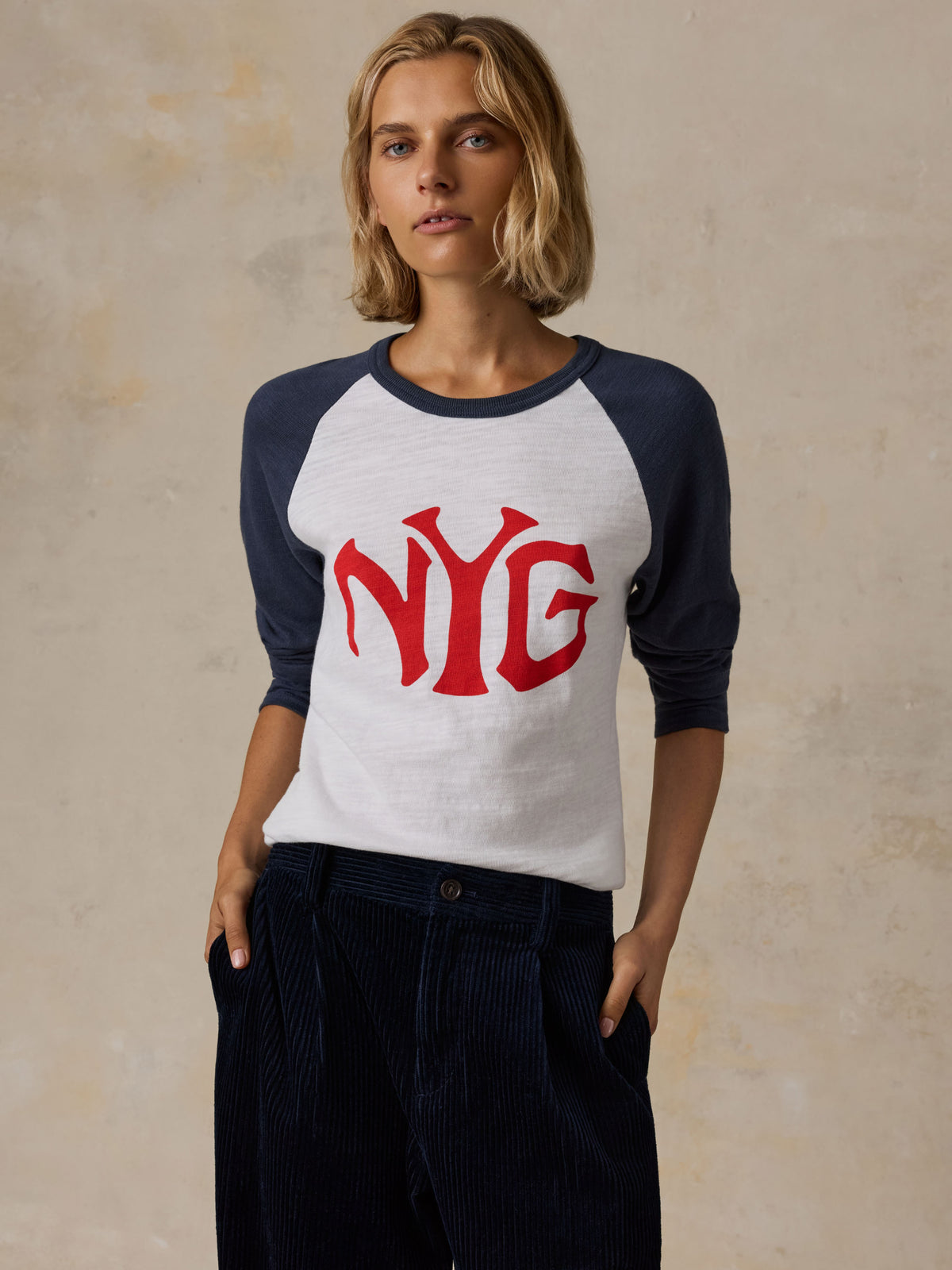 A woman wearing a white and blue NY Giants baseball tee with navy pants, image 5 of 5